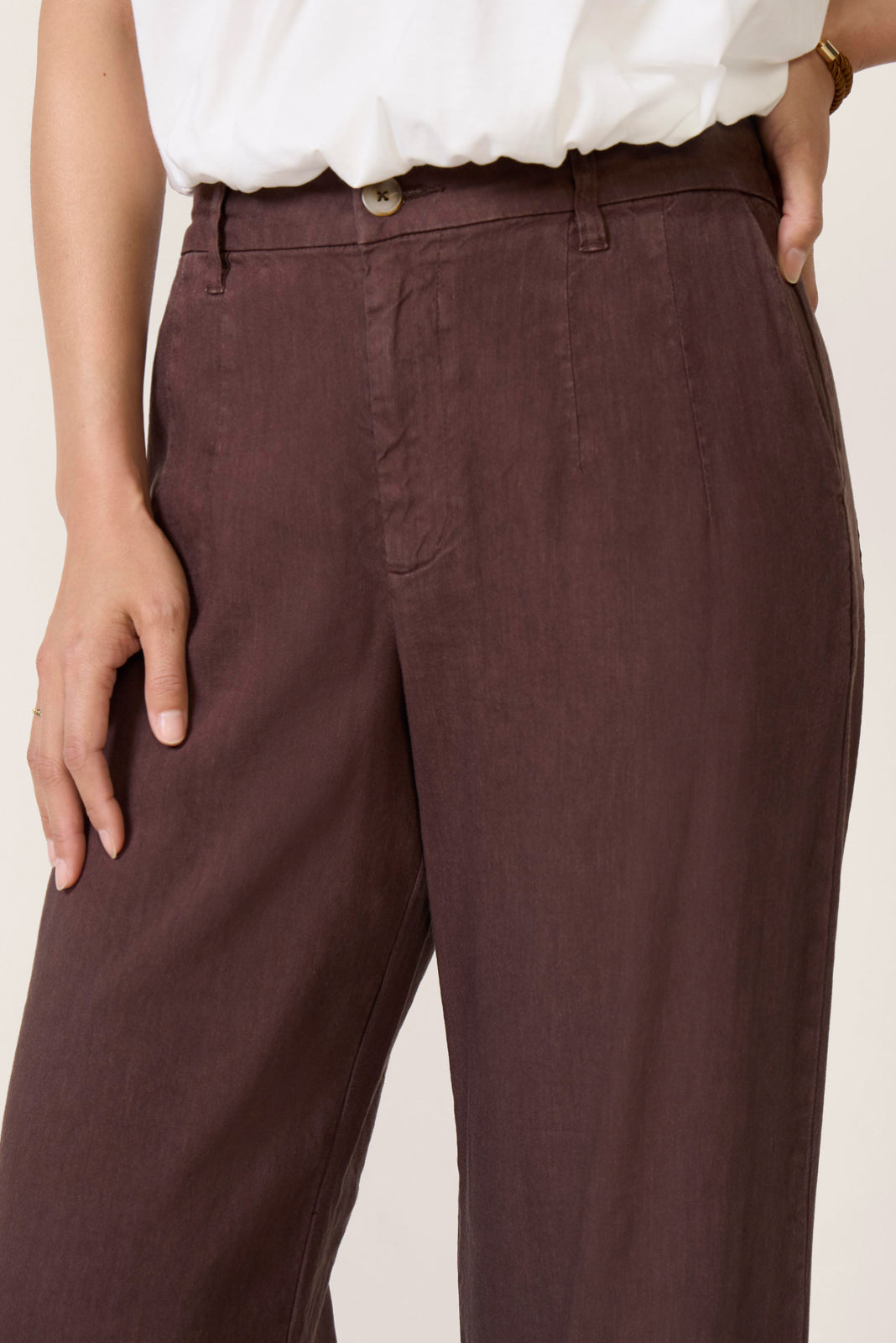 Woman wearing chocolate brown linen pants paired with white blouse, showing relaxed fit