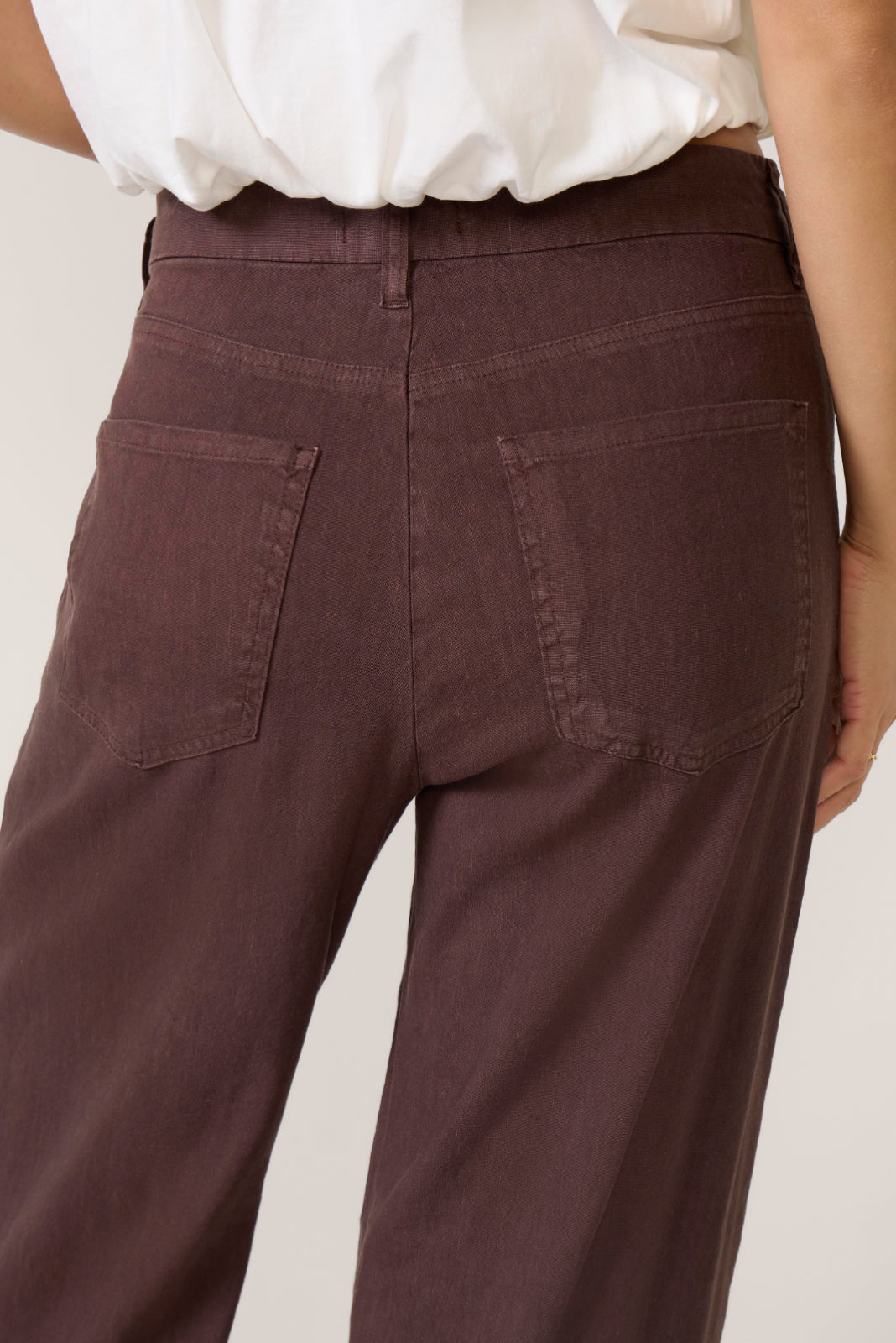 Back view of woman wearing chocolate brown linen pants with white top