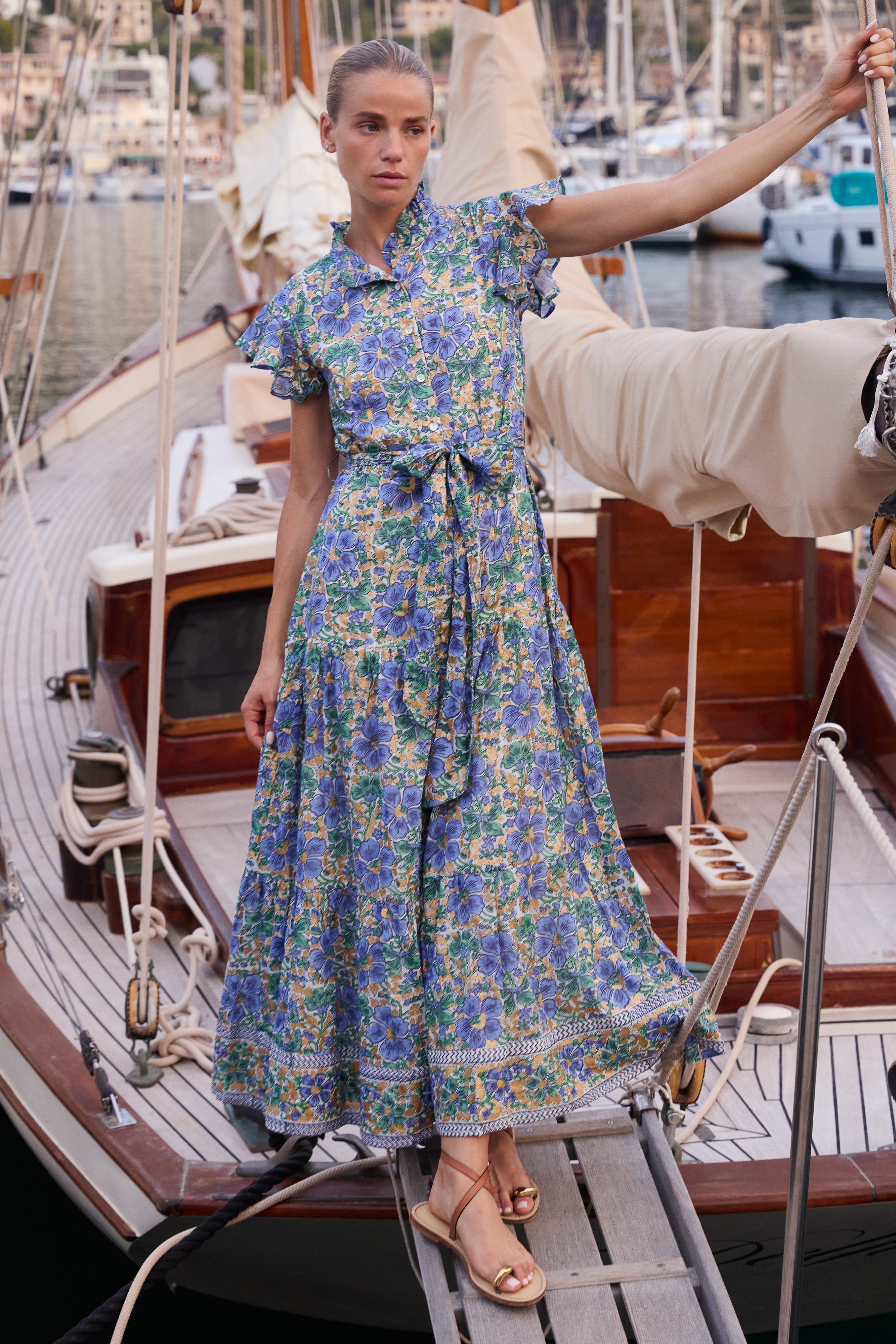 Woman wearing blue floral maxi dress with ruffle collar on yacht deck