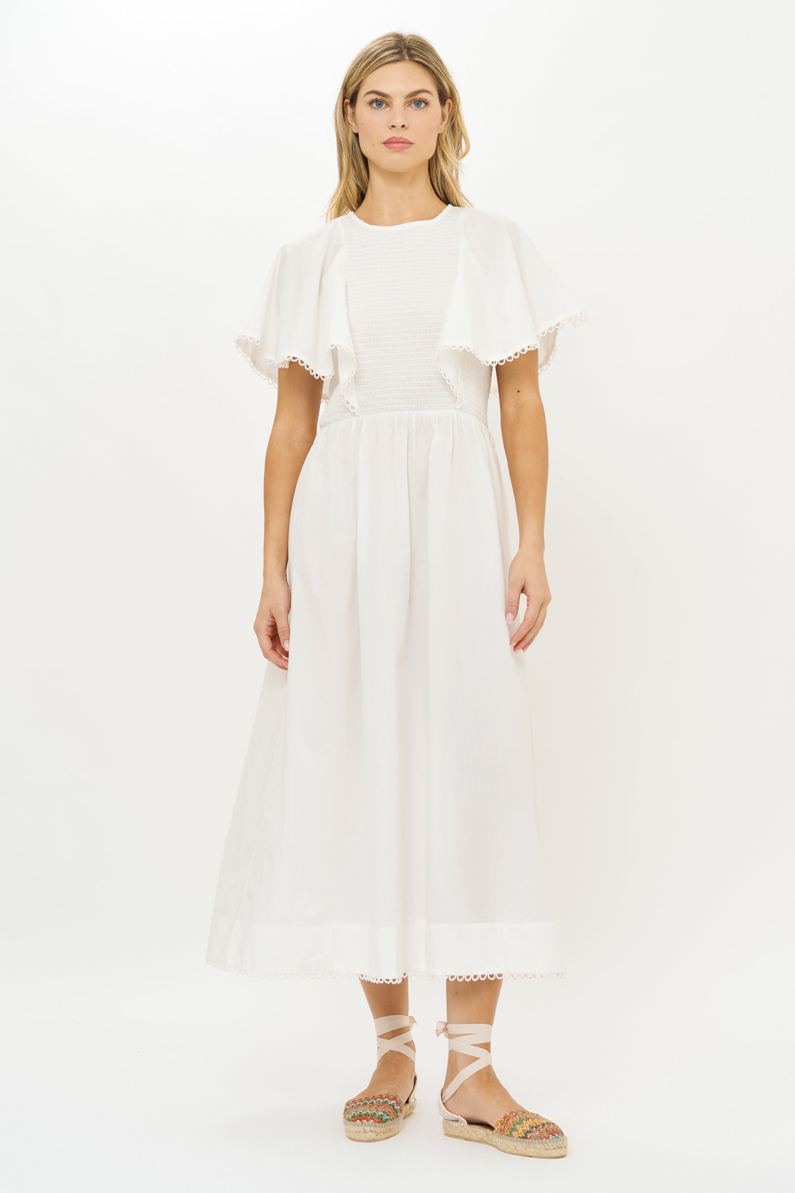 White eyelet midi dress with short sleeves and scalloped lace trim worn with espadrilles