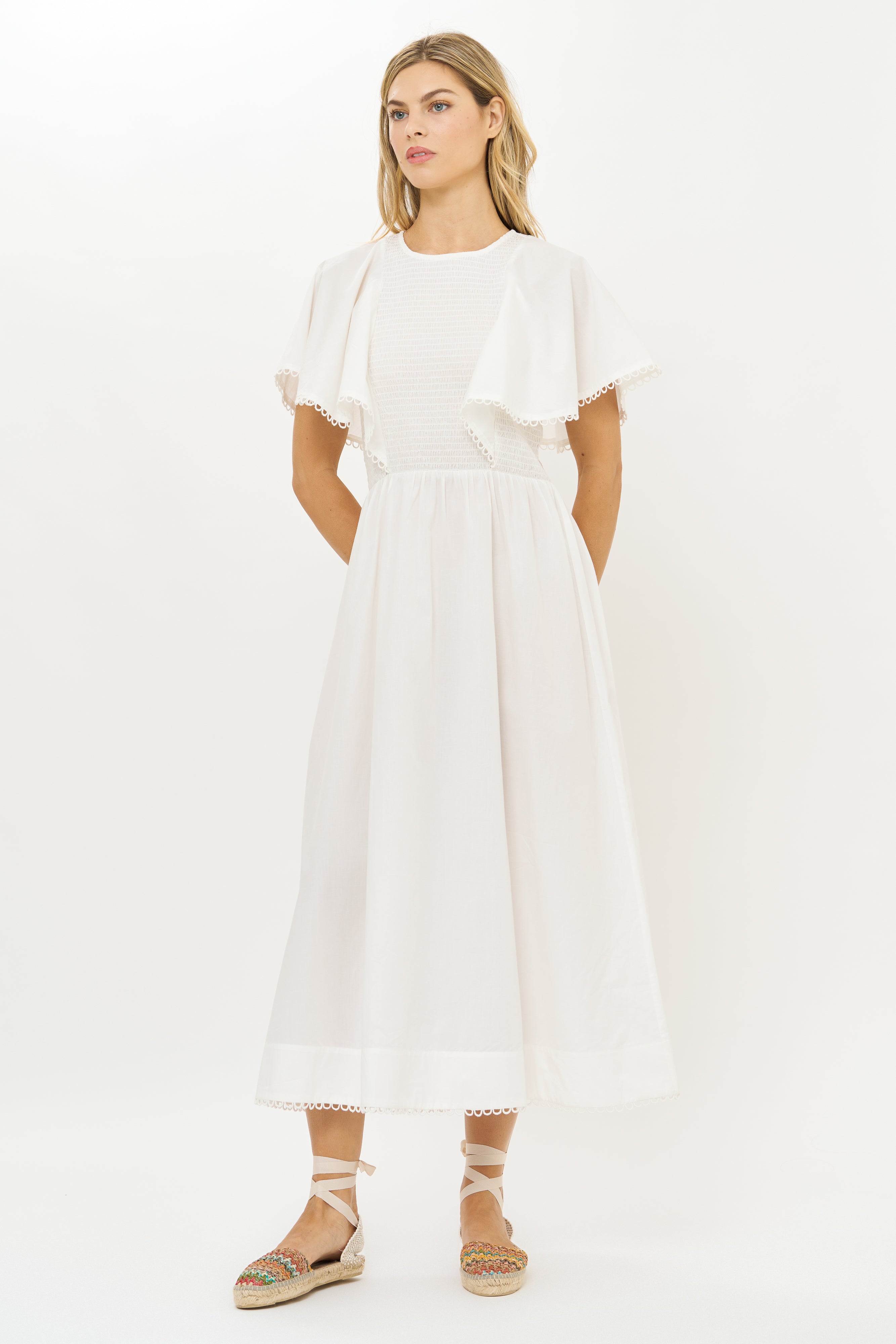 White eyelet midi dress with flutter sleeves and lace trim worn with espadrilles
