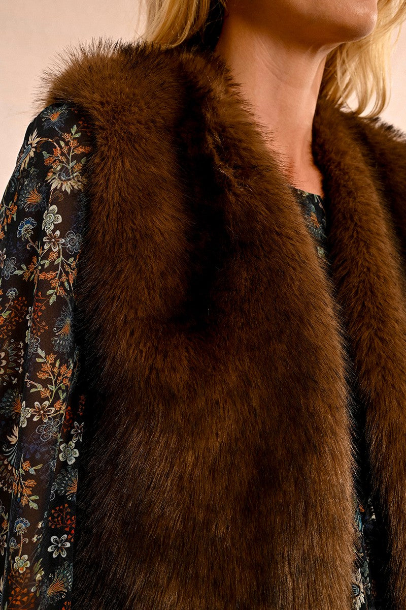 Woman wearing chocolate brown faux fur vest over floral print blouse