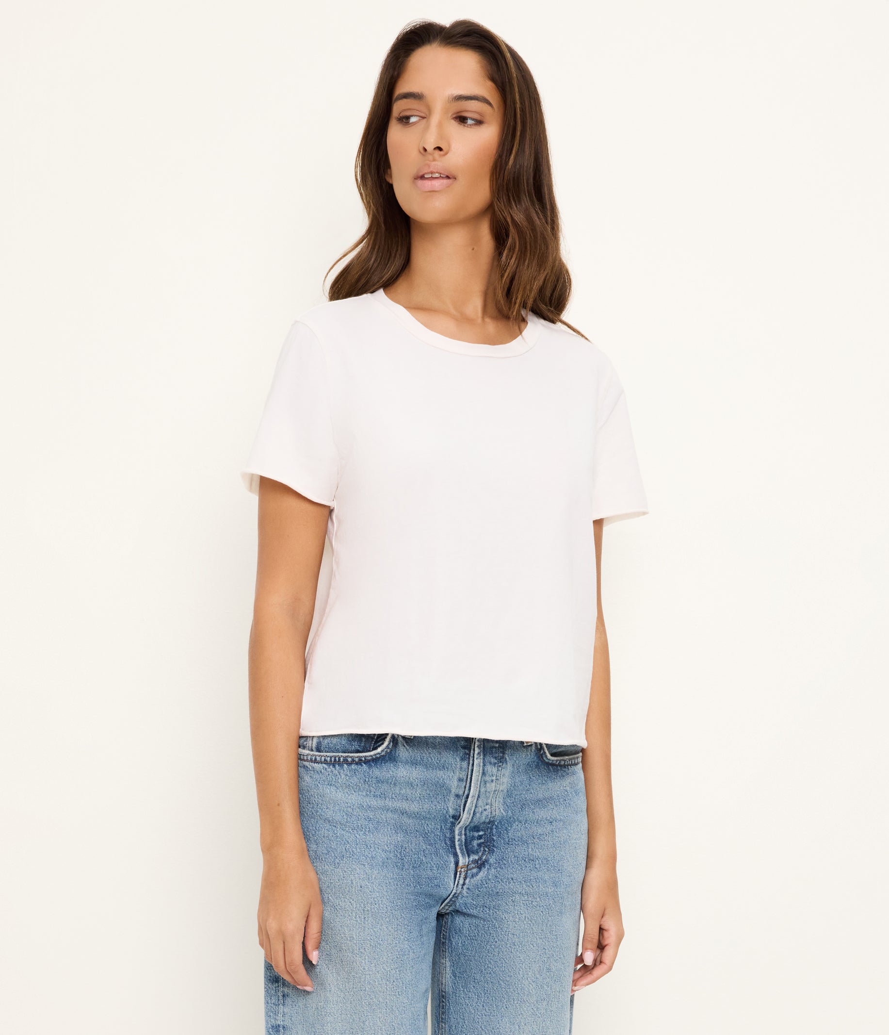 Woman wearing white short-sleeve crop t-shirt with rolled hem and blue jeans