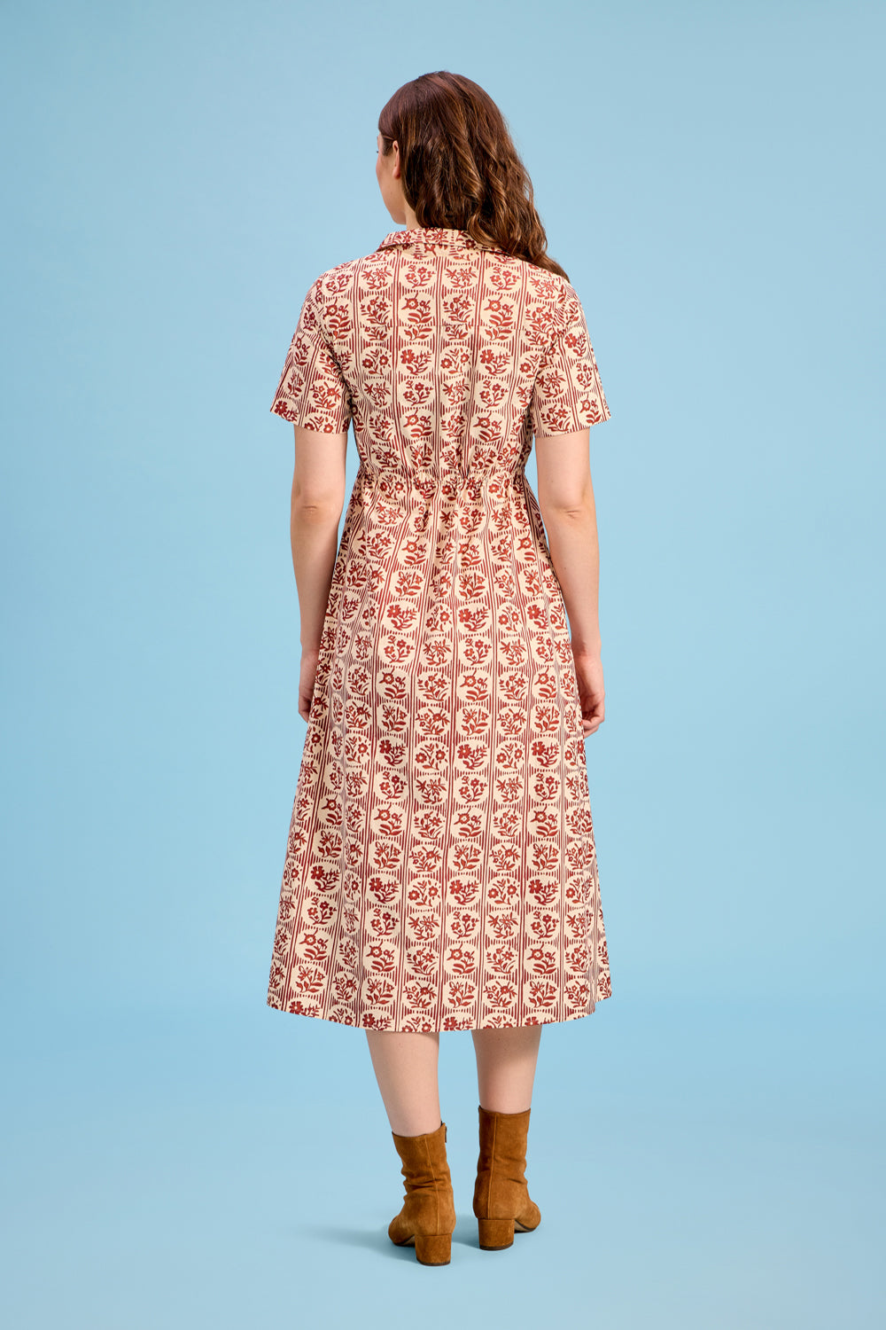 Back view of midi shirt dress in cream with brick red floral block print, worn with tan boots