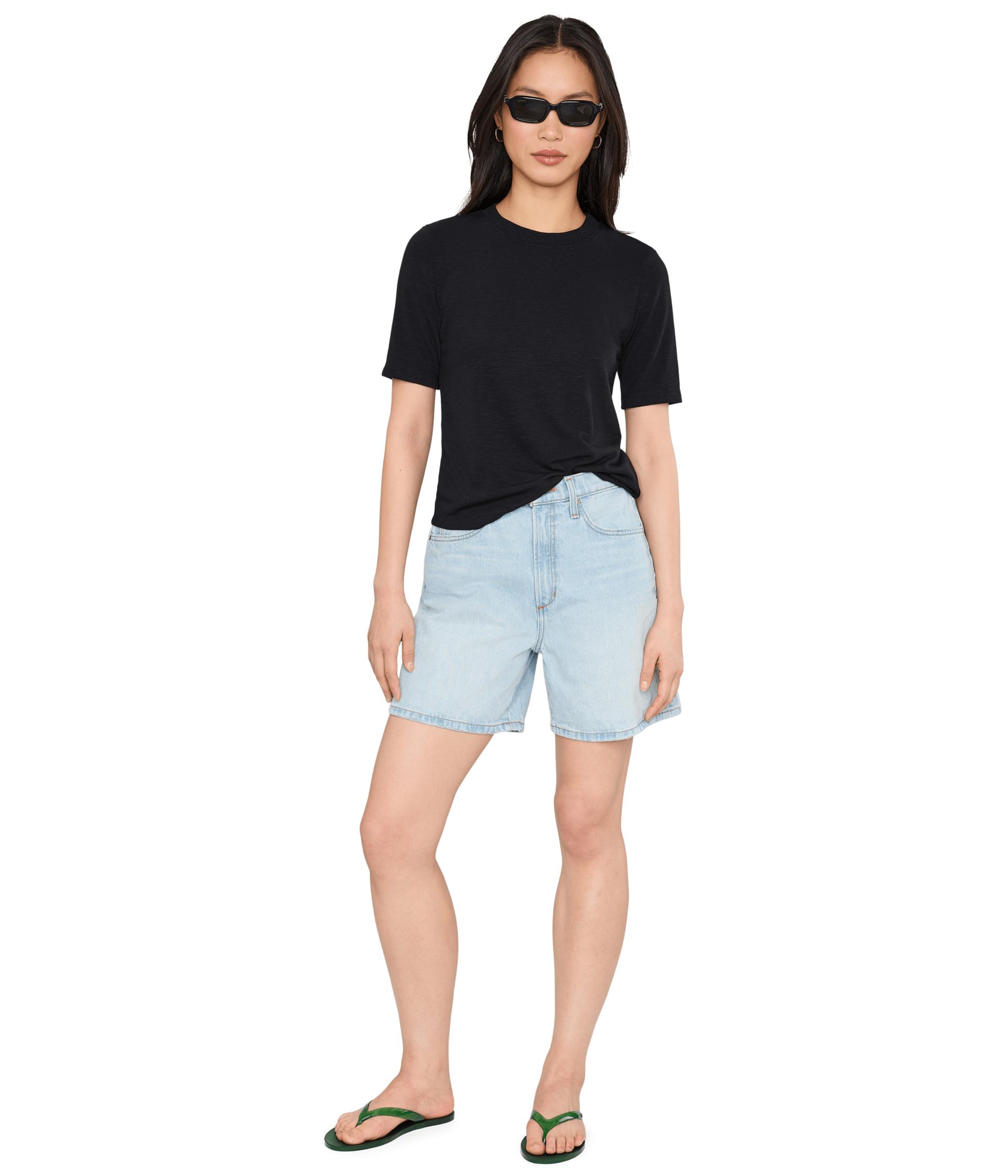 Woman wearing black crew neck t-shirt with light wash denim shorts and sunglasses