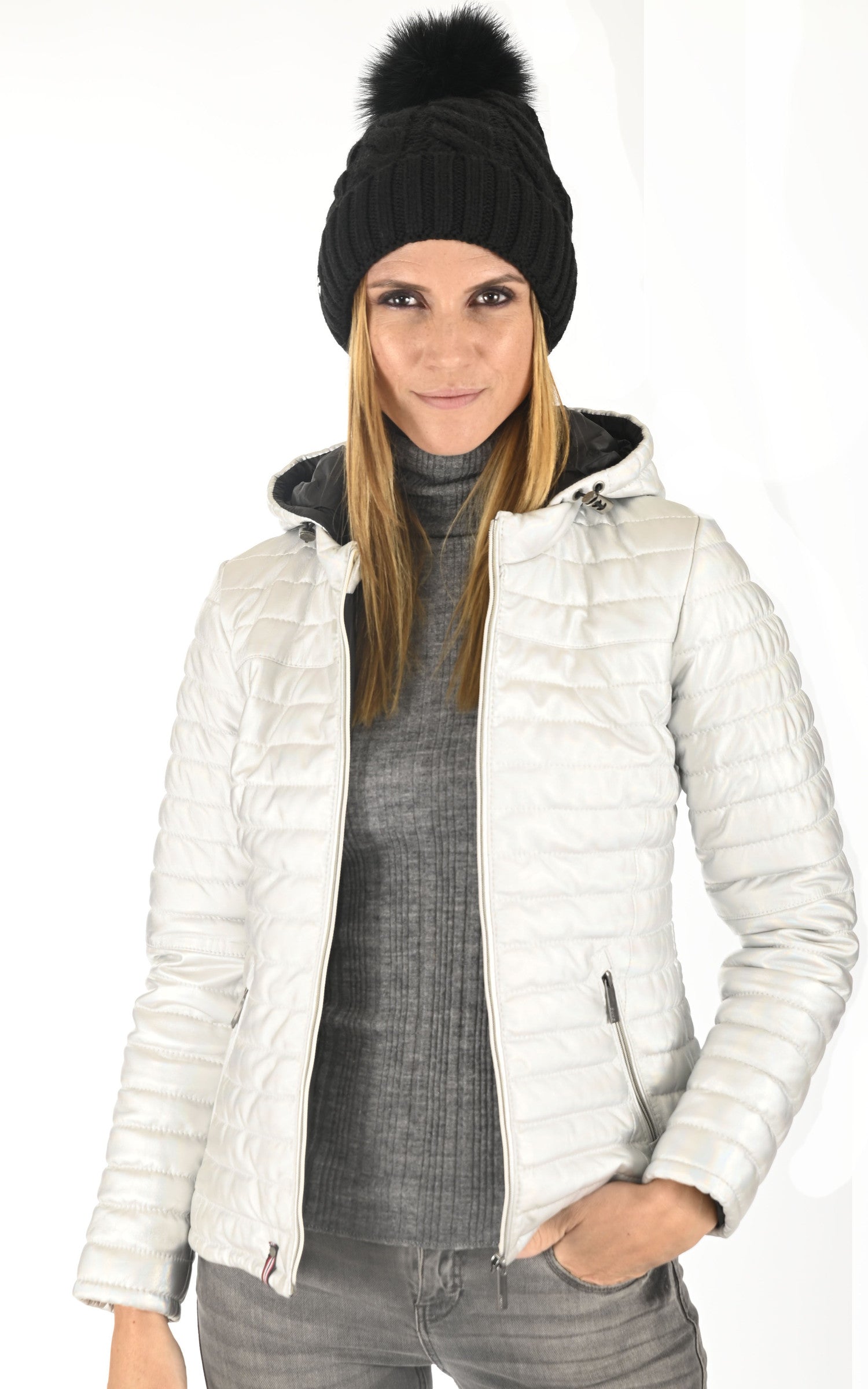 Woman wearing black knit beanie hat with fur pom pom and white winter jacket