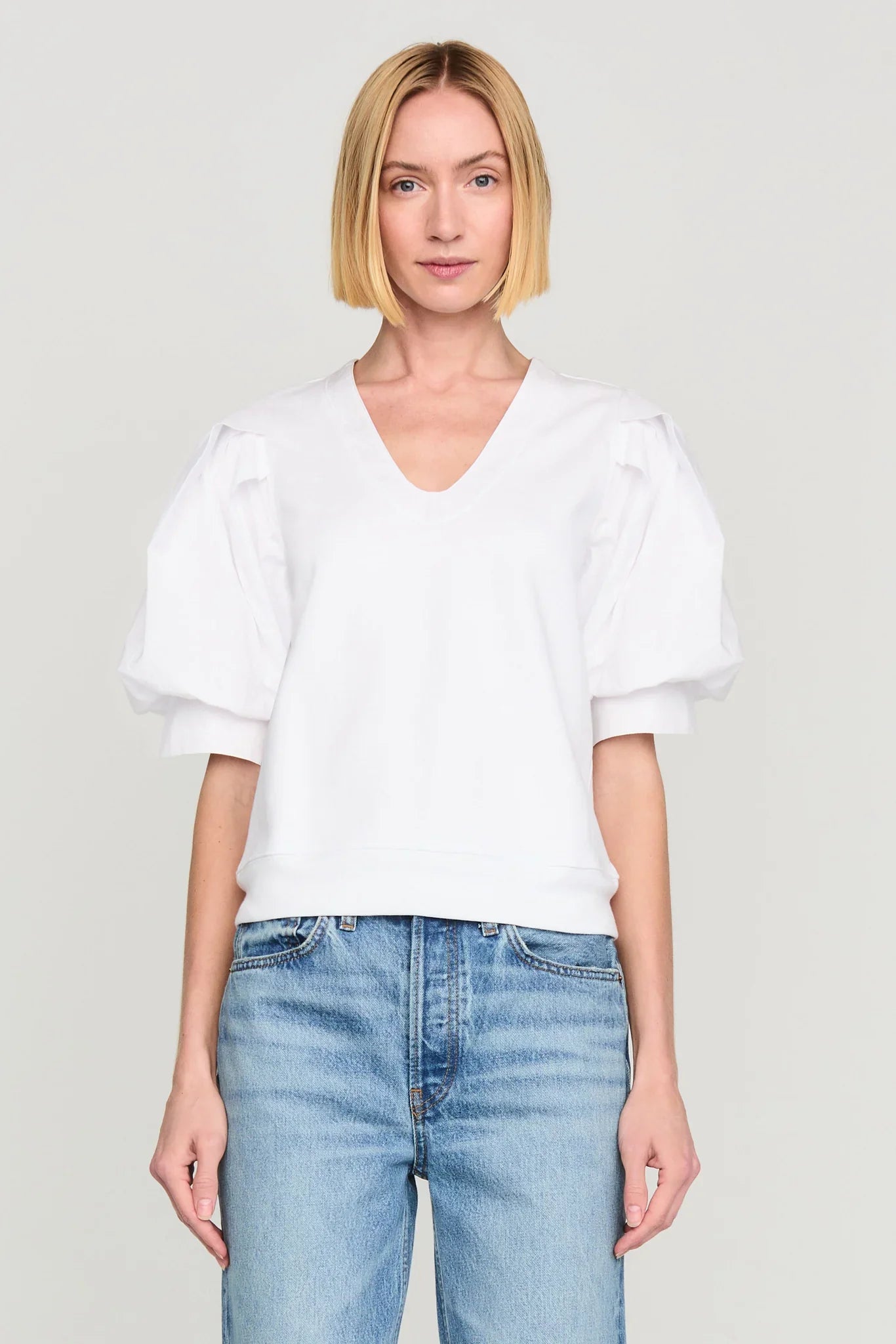 Woman wearing white Marie Oliver Viva Popover top with puff sleeves and blue jeans