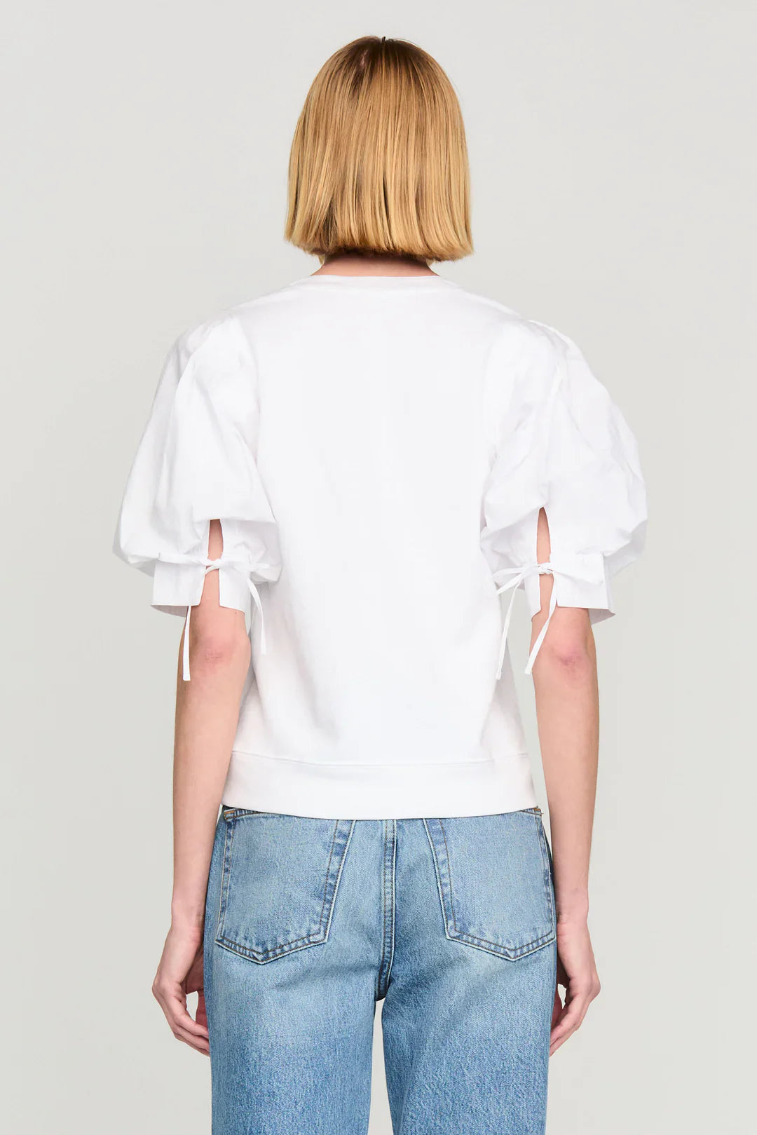 Back view of white Marie Oliver Viva Popover top with tie sleeves and blue jeans