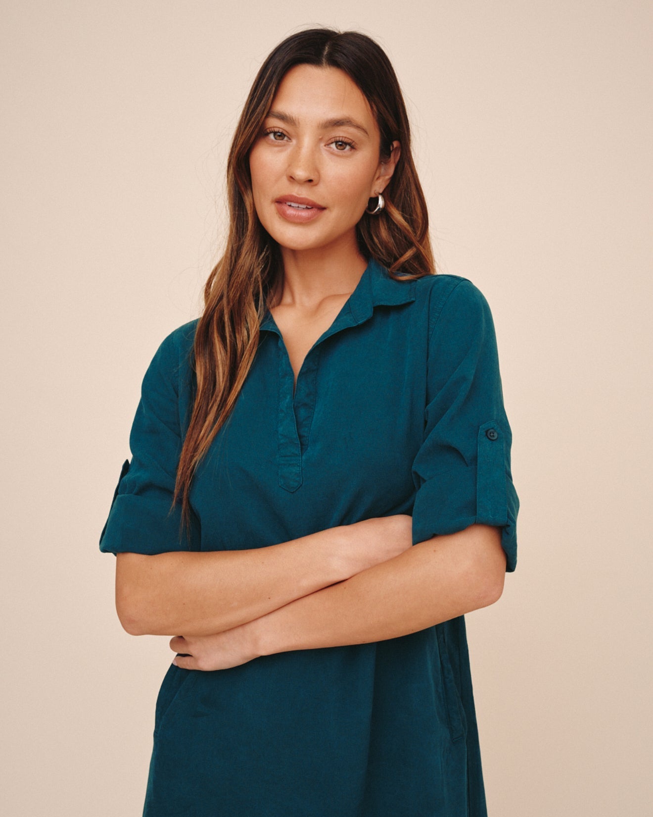 Woman wearing Bella Dahl teal A-line dress with rolled sleeves and collar, arms crossed