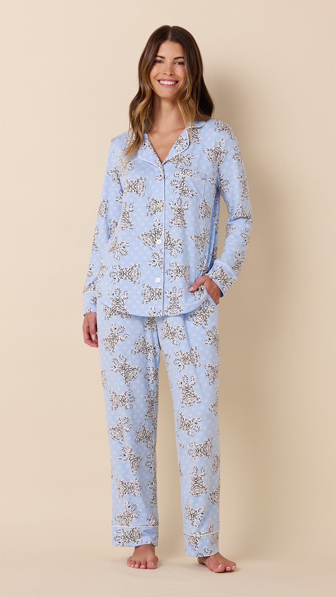 Woman wearing light blue long-sleeve button-front pajama set with white Bengal tiger print