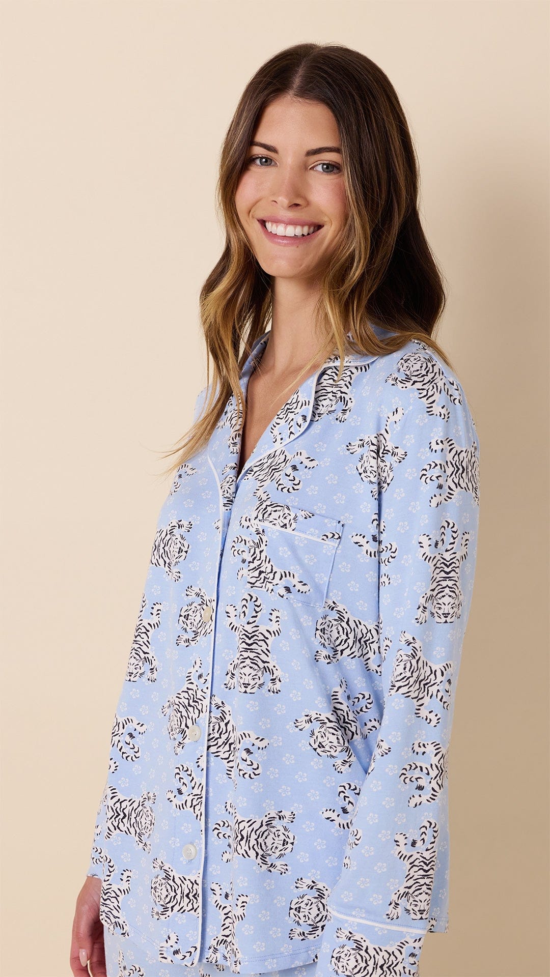 Woman wearing light blue long-sleeve pajama top with white Bengal tiger print pattern