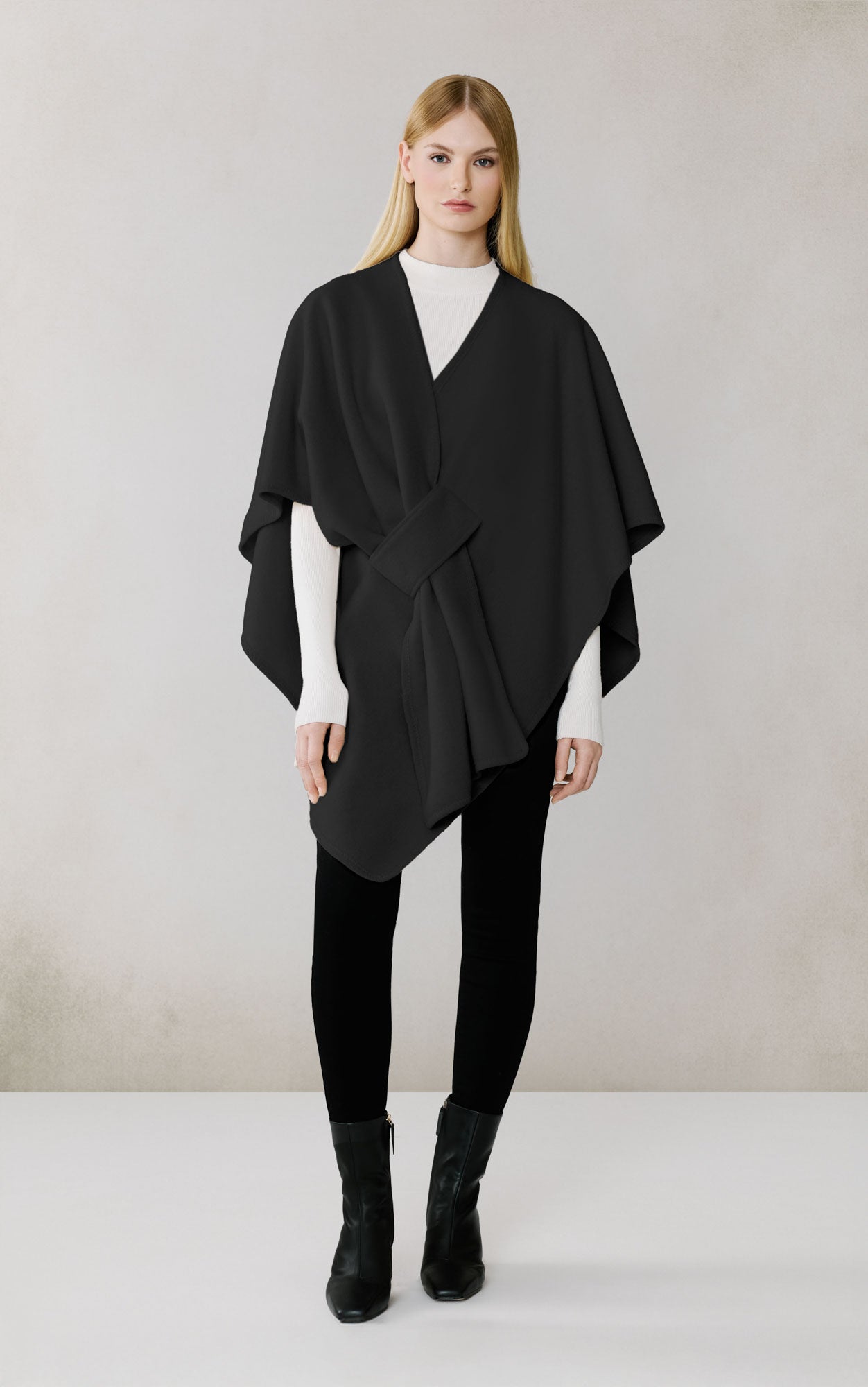 Woman wearing black draped scarf over white top and black pants with boots