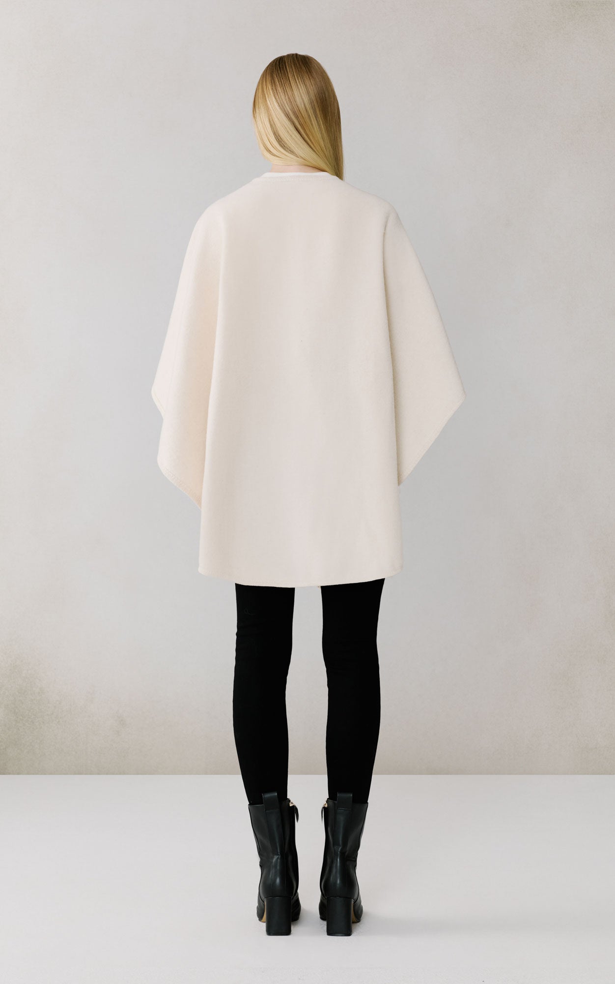 Woman wearing cream colored oversized scarf or wrap, back view, professional studio setting