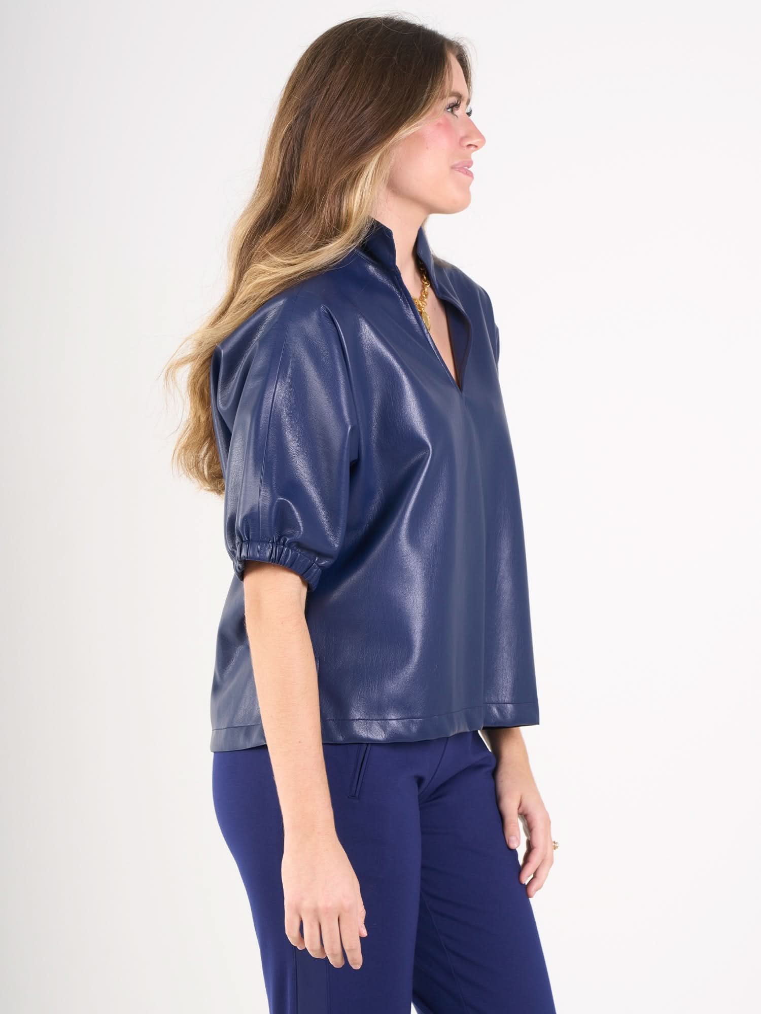 Woman wearing navy blue vegan leather top with gathered sleeves and v-neck