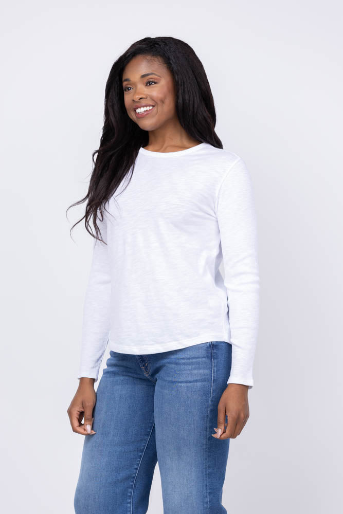 Woman wearing white long sleeve ribbed tee shirt with blue jeans on neutral background