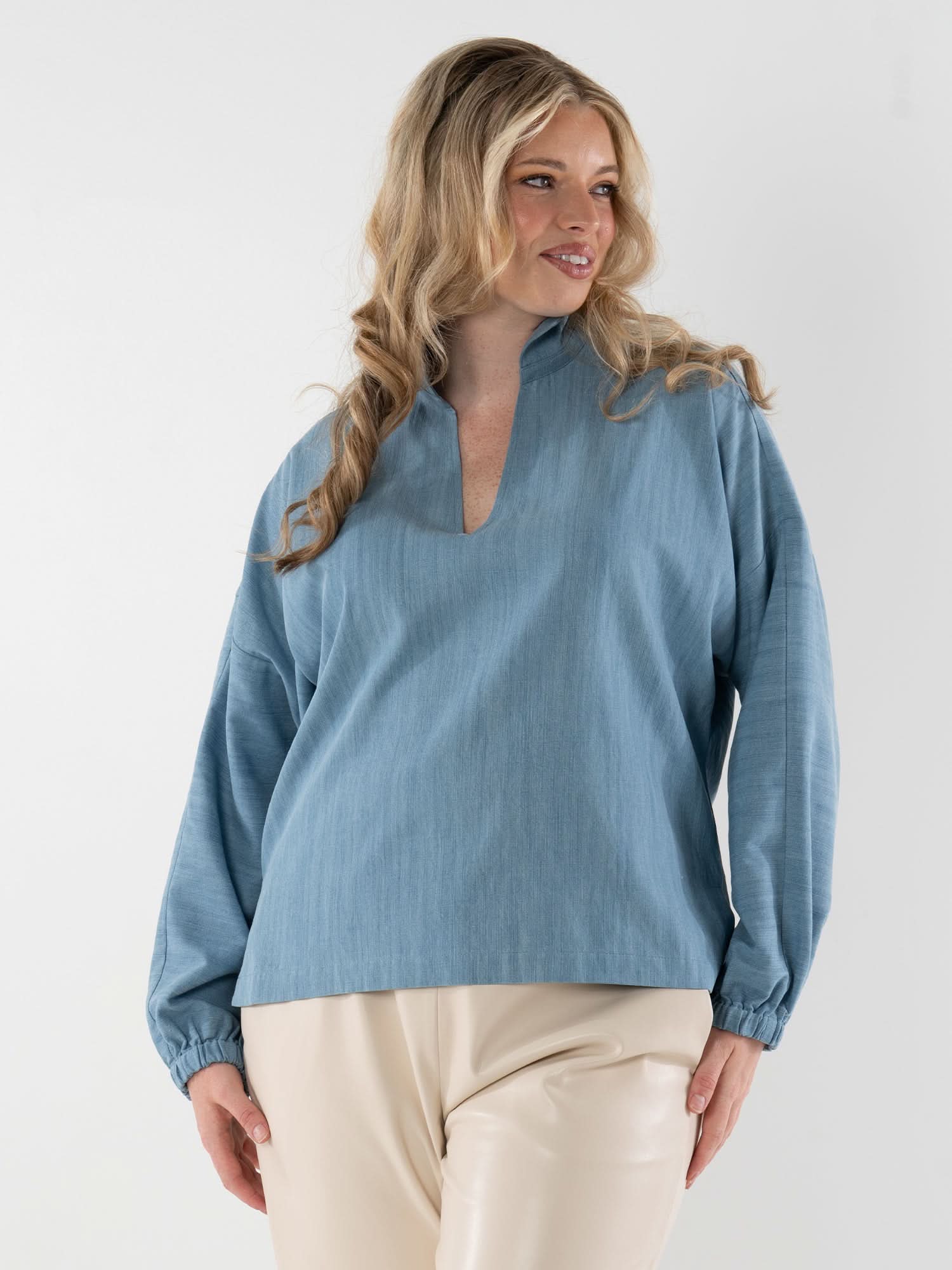 Woman wearing light blue denim long sleeve pullover with cream colored pants