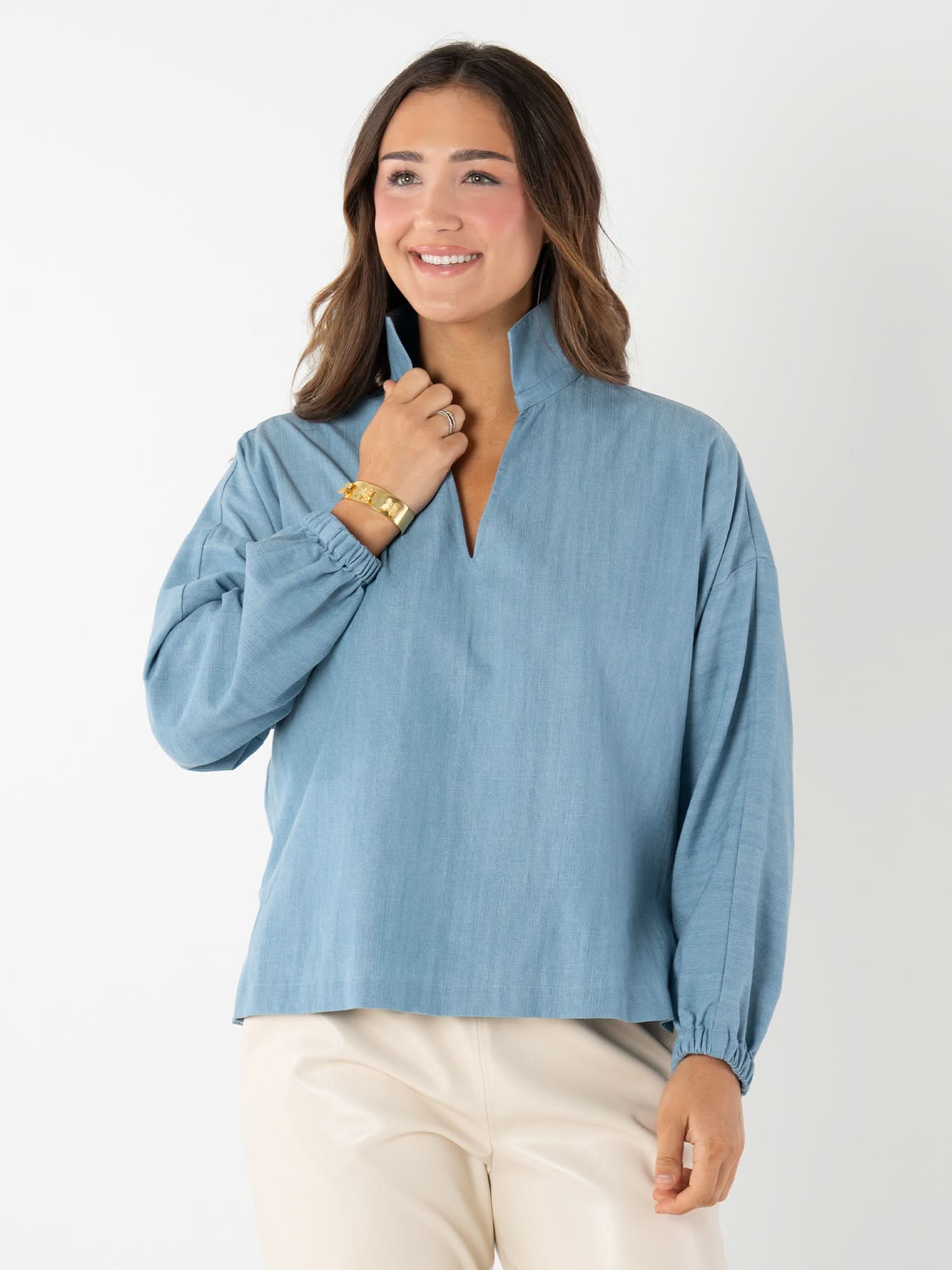 Woman wearing light blue denim long sleeve pullover with v-neck and gathered sleeves