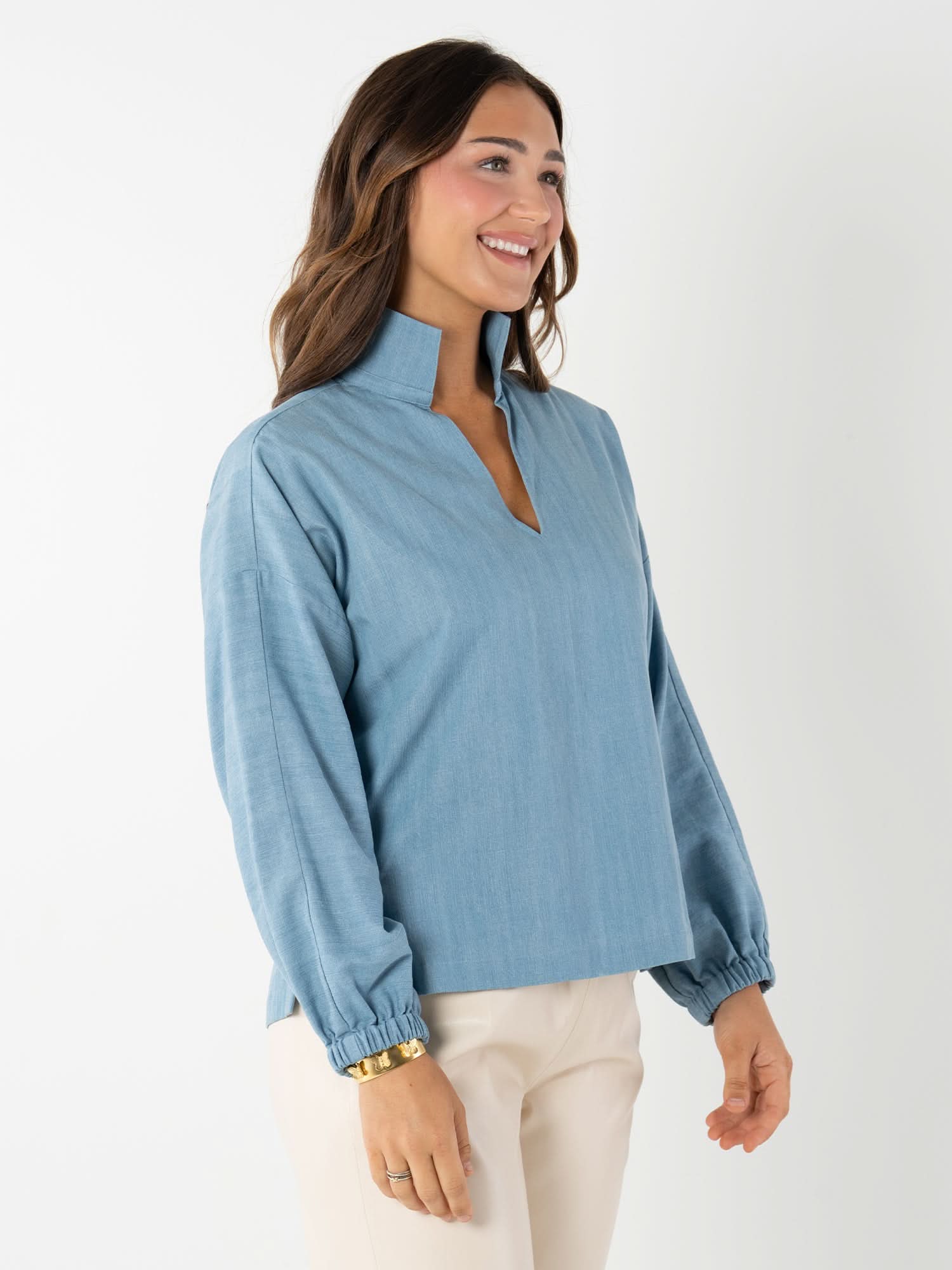 Woman wearing light blue denim long sleeve pullover with elastic cuffs and stand collar