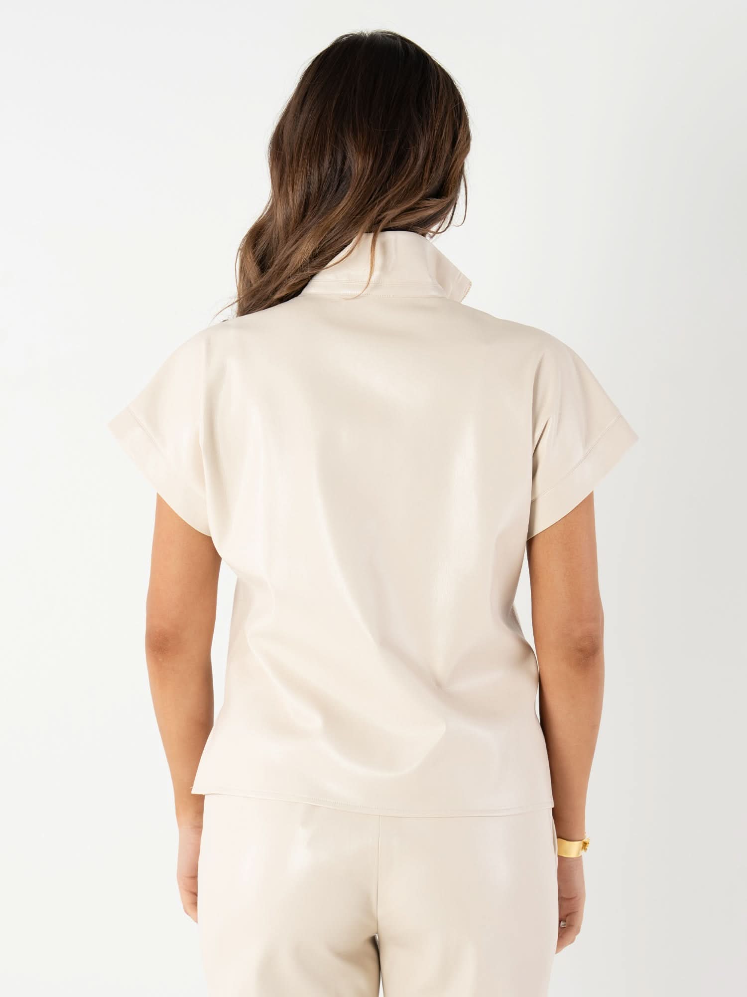 Back view of woman wearing cream colored short sleeve vegan leather top