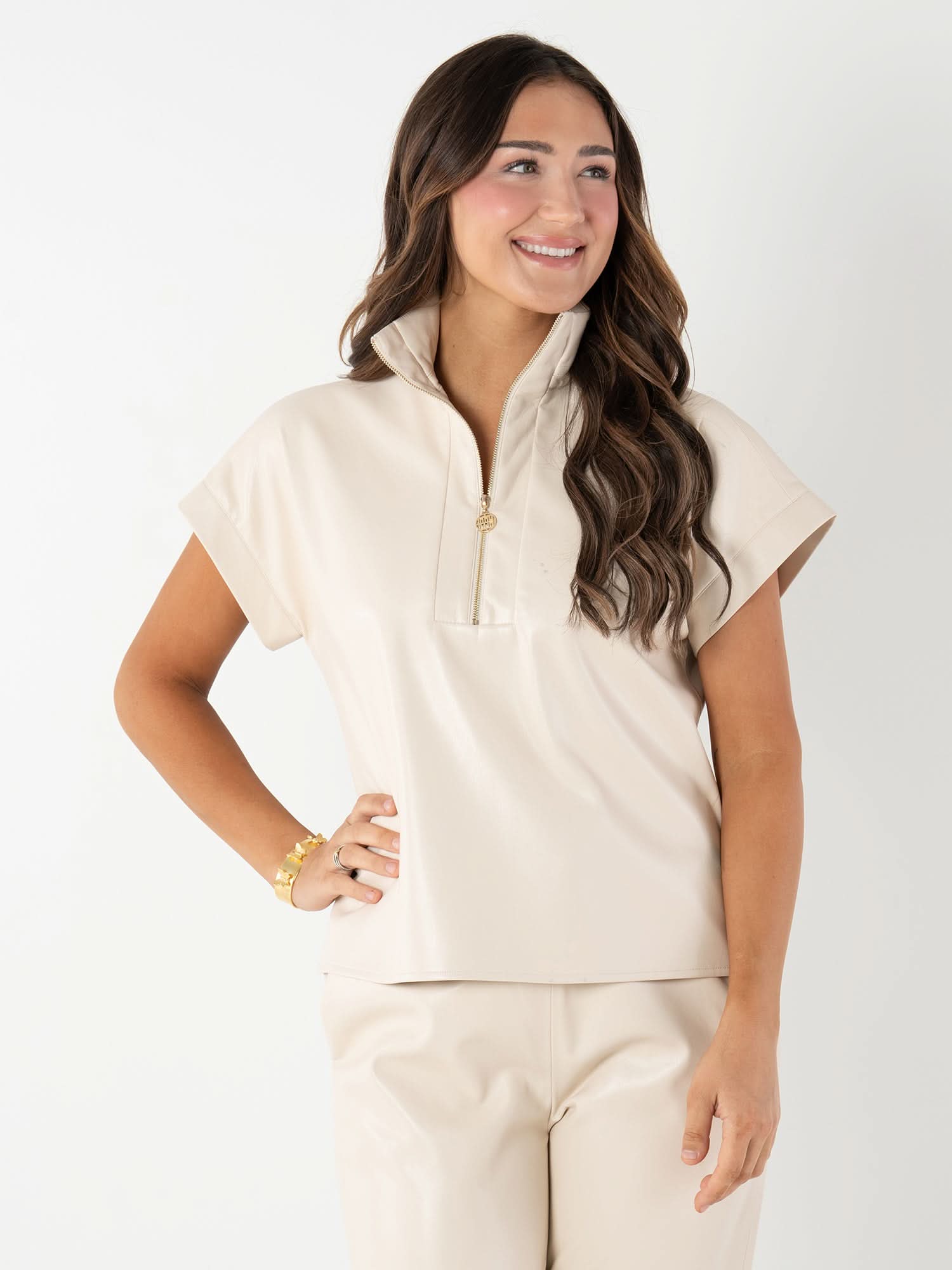 Woman wearing beige vegan leather short sleeve pullover top with quarter zip