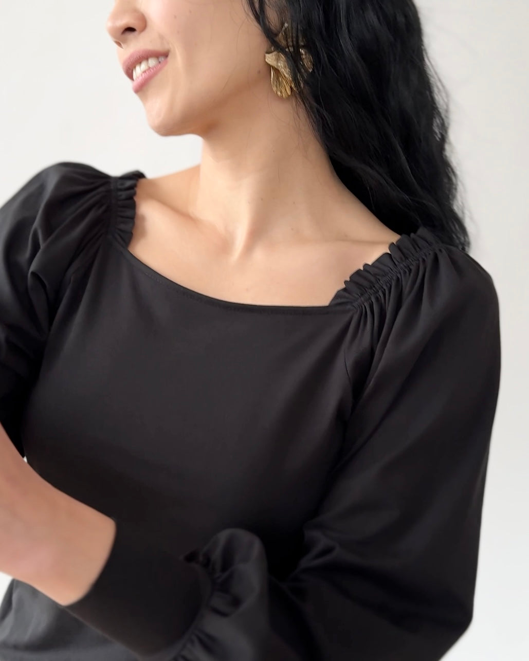 Black off-shoulder top with ruched neckline and puffy sleeves worn by model