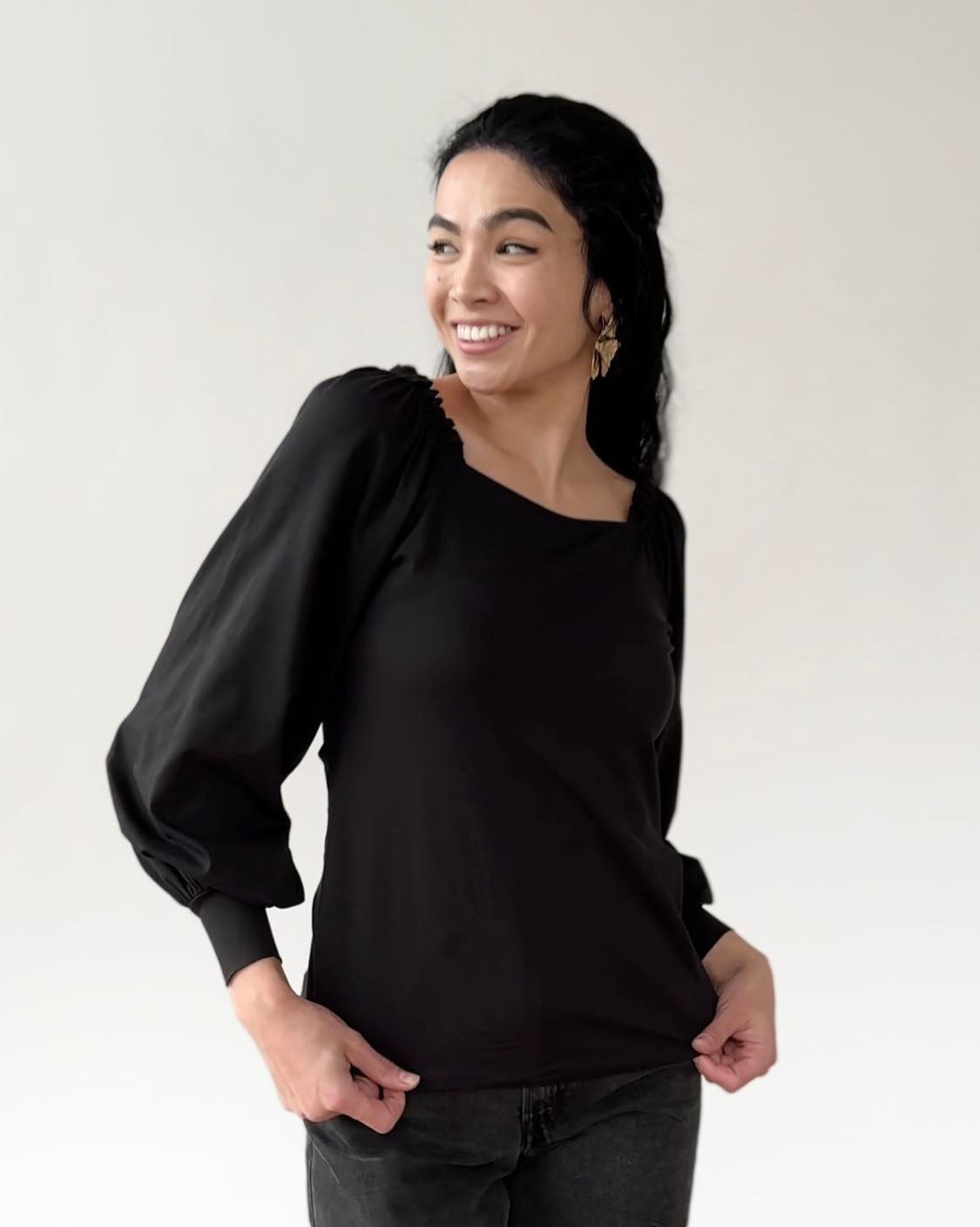 Black long-sleeve top with puffy sleeves and fitted silhouette on smiling model