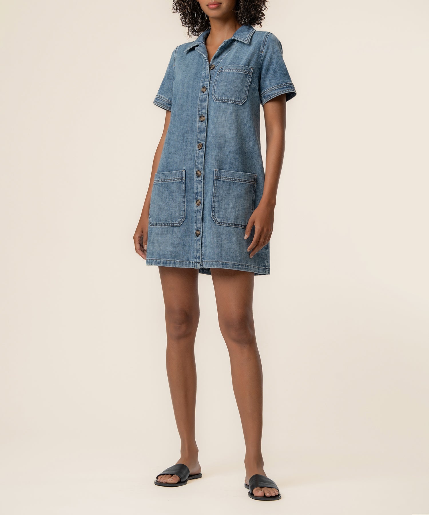 Woman wearing medium wash denim button-front shirt dress with short sleeves and pockets