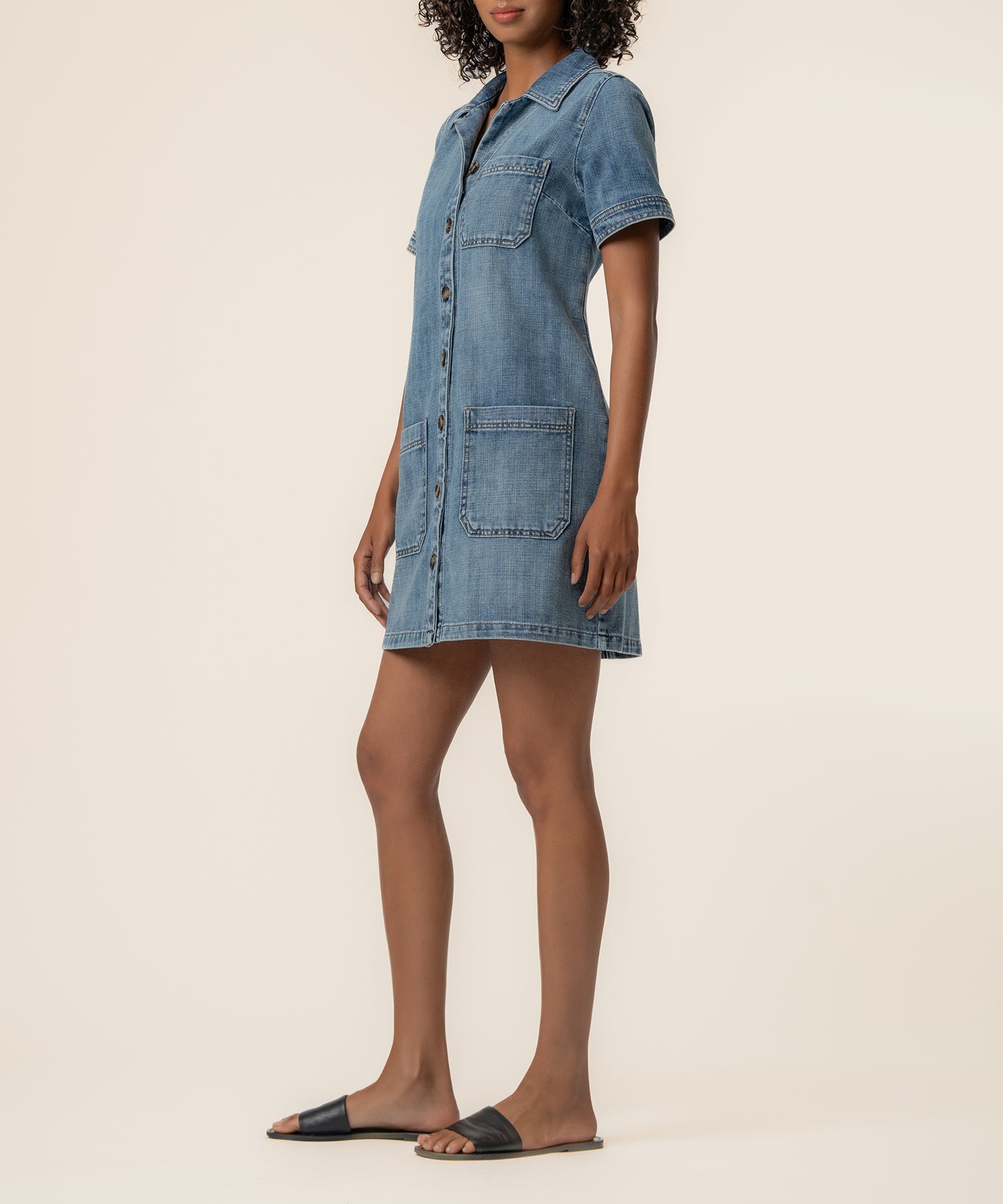 Woman wearing light blue denim shirt dress with button front and pockets