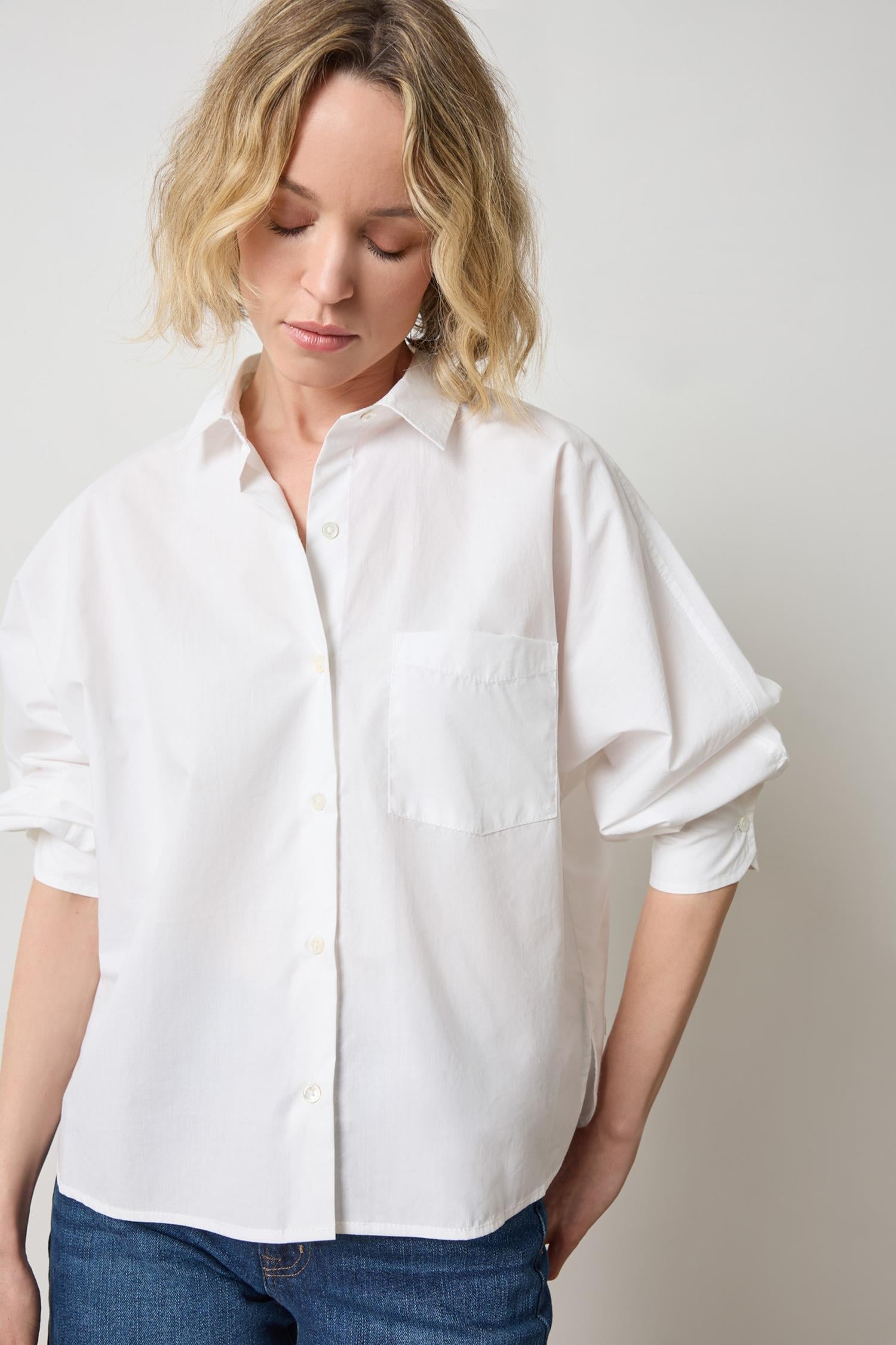 Woman wearing white dolman sleeve button-down blouse with rolled sleeves and chest pocket
