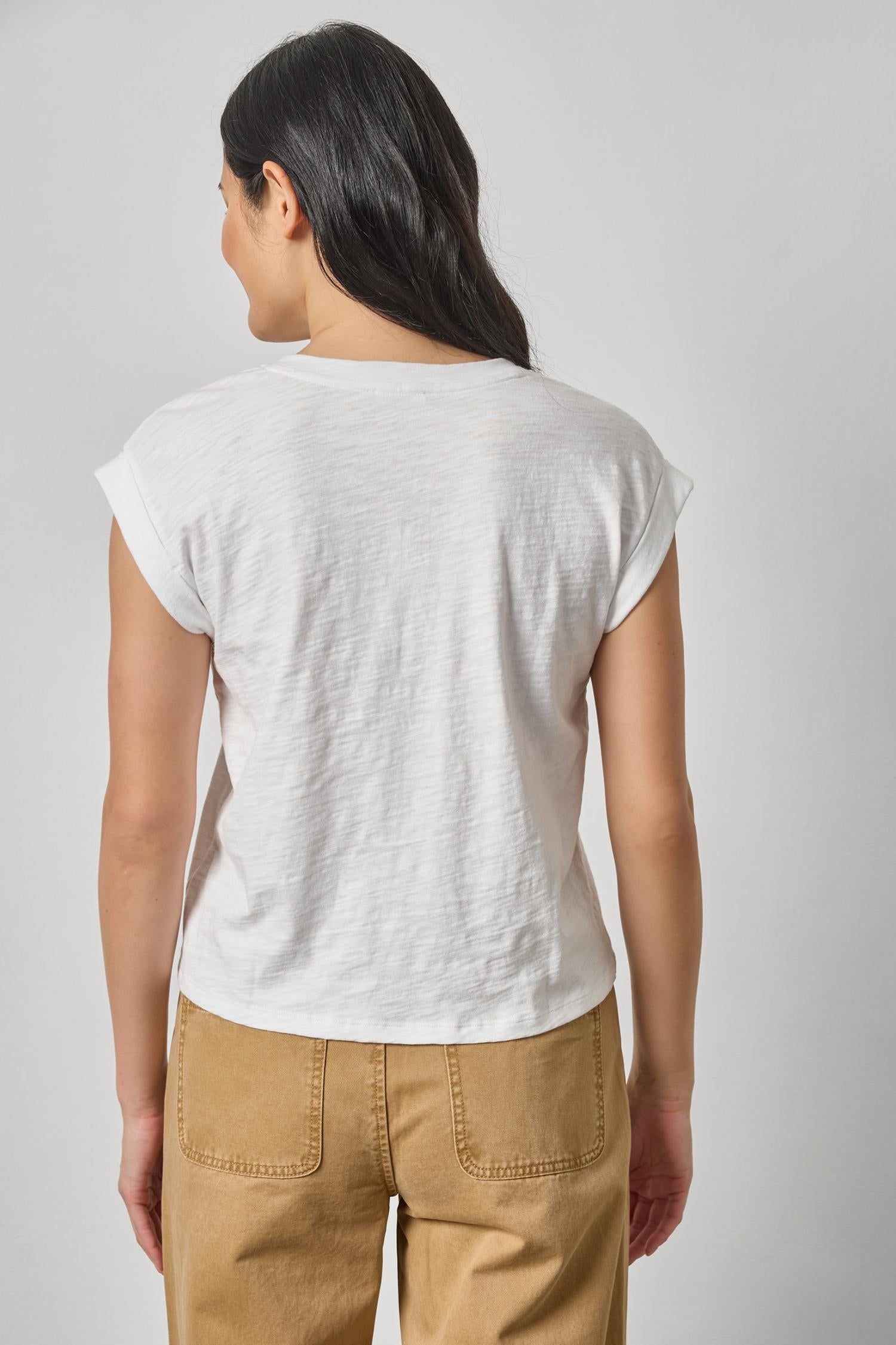 Back view of woman wearing white cuff sleeve boxy top with tan pants