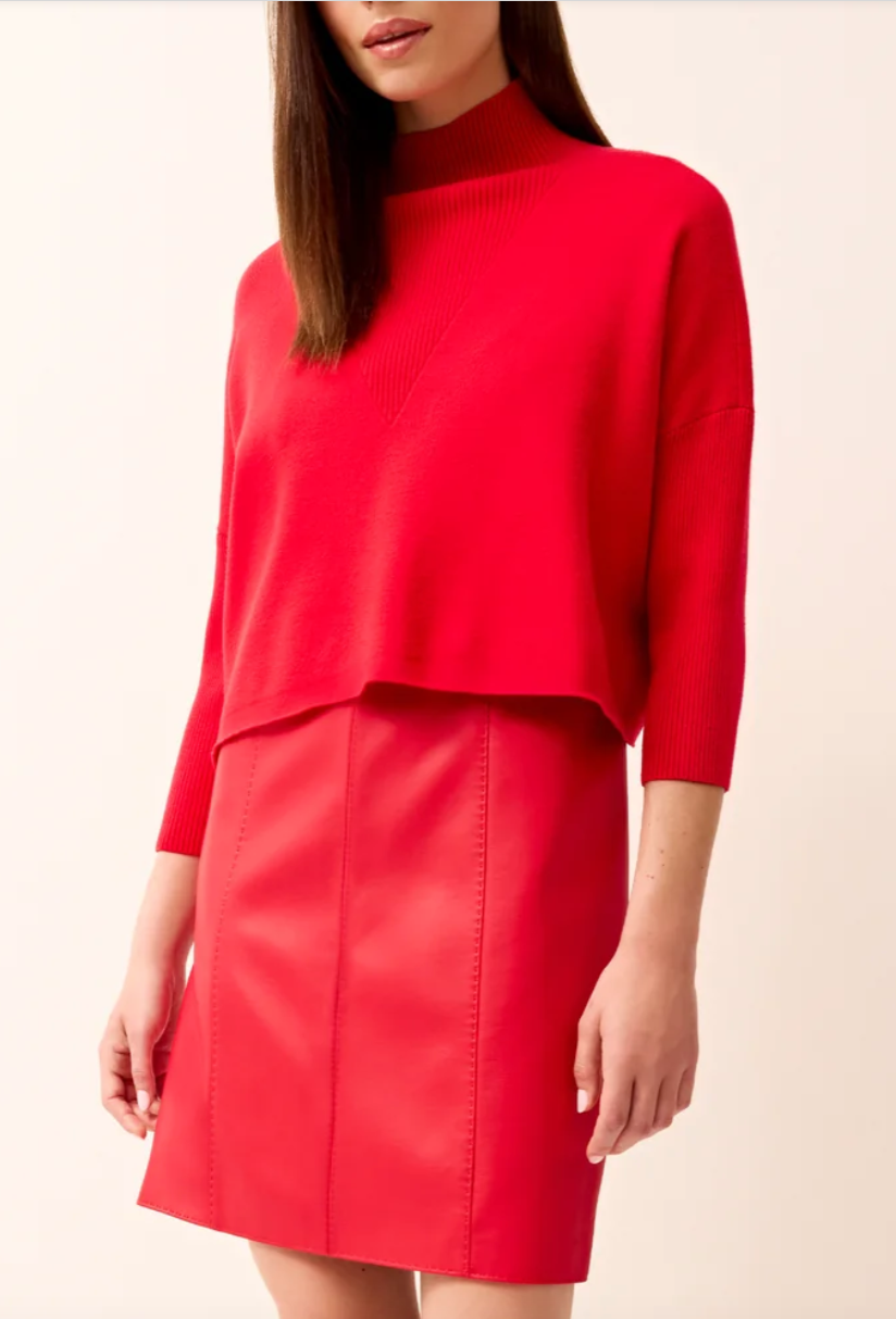 Woman wearing red mock neck sweater and matching red mini skirt