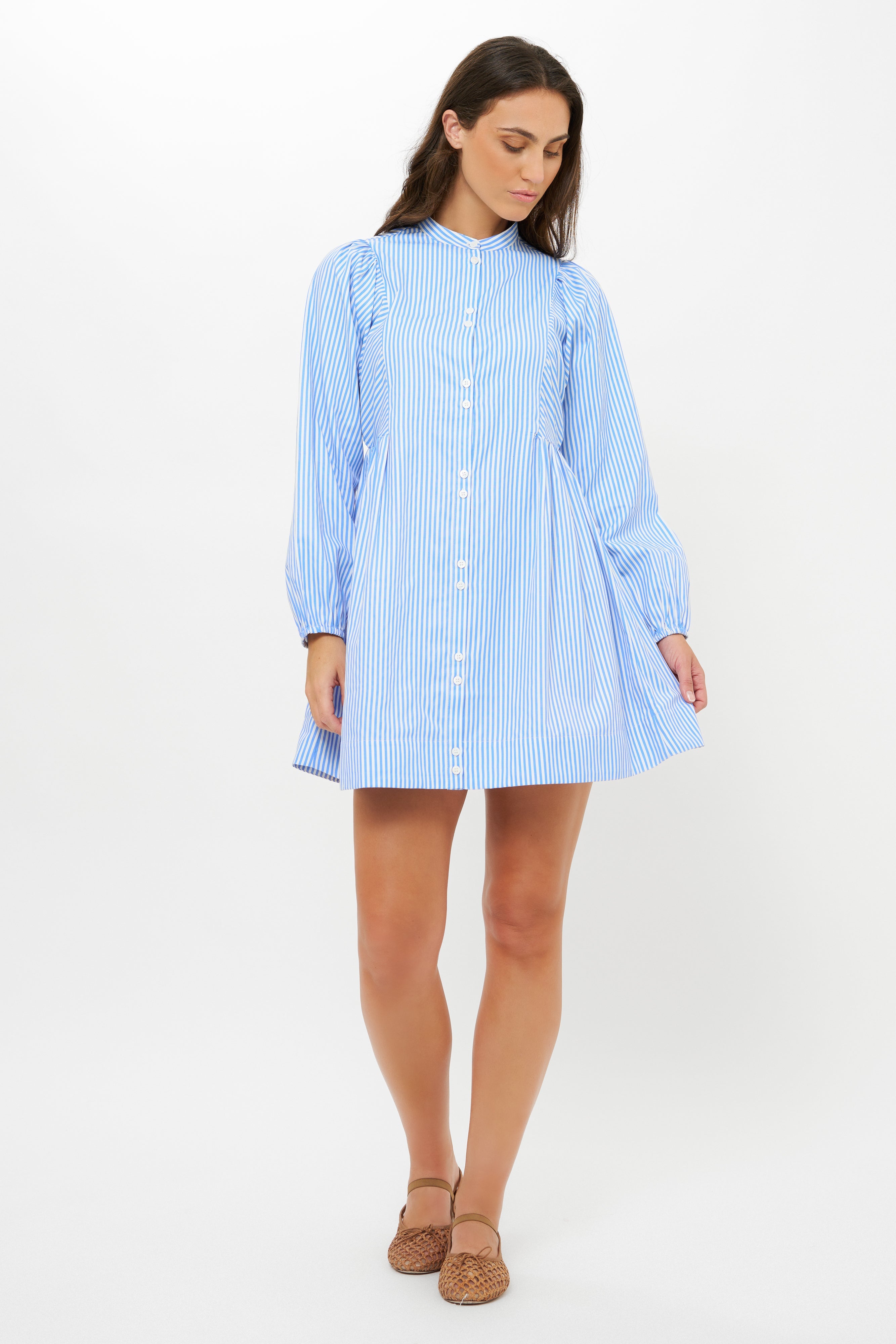 Woman wearing blue and white striped button-front shirt dress with long sleeves