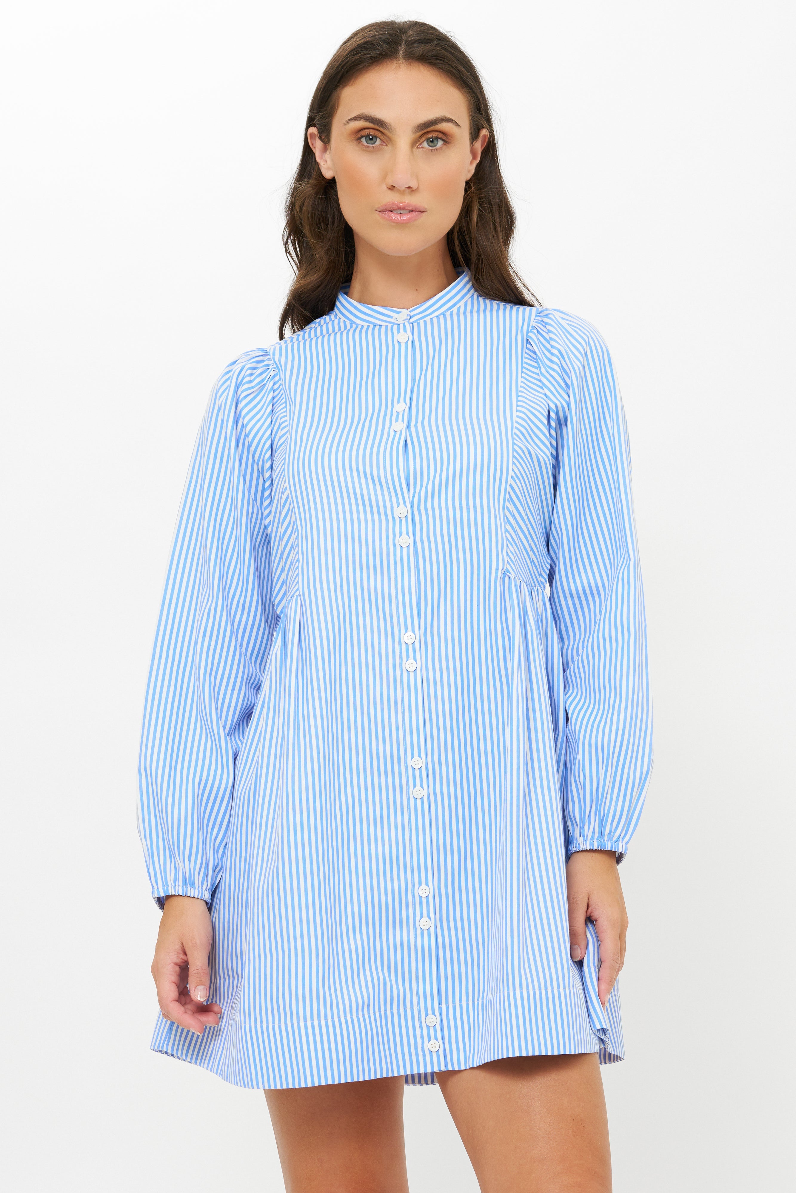 Woman wearing blue and white striped button-front shirt dress with long sleeves