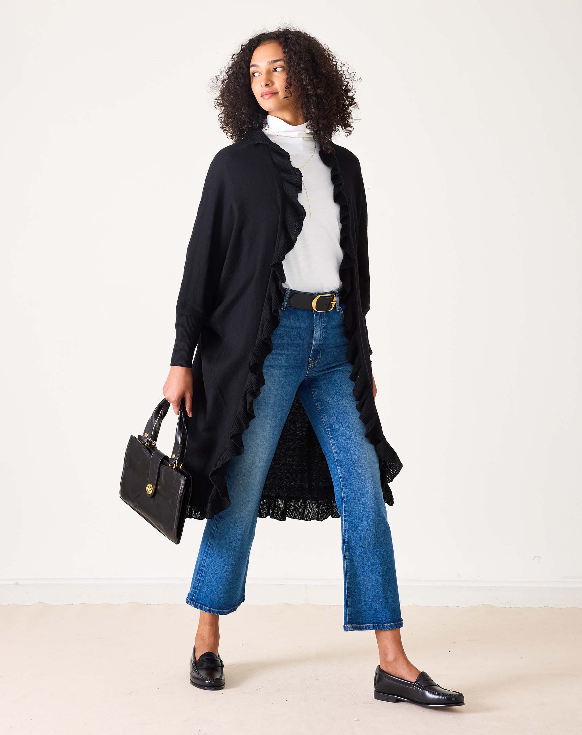 Model wearing black ruffle-trimmed Chelsea Kimono cardigan over white turtleneck with blue jeans