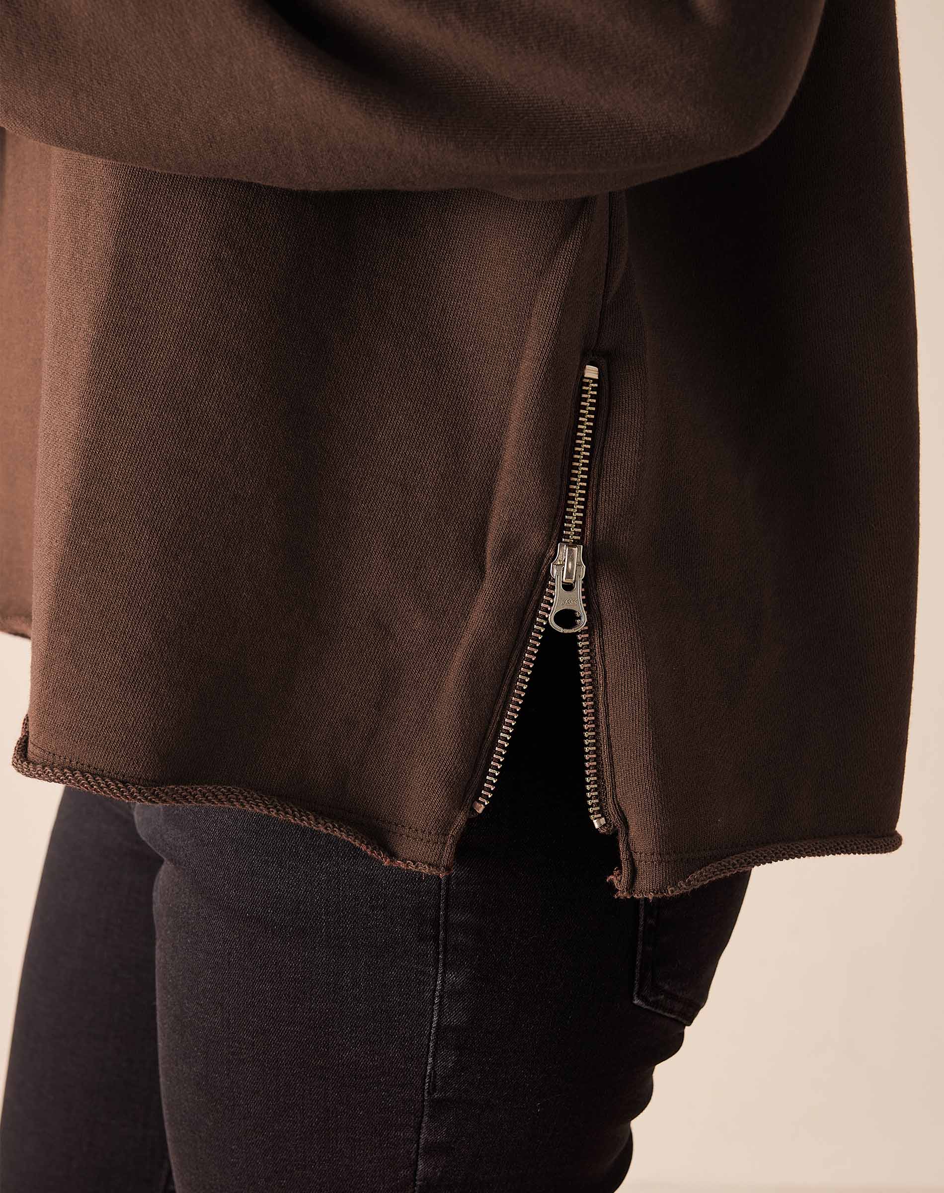 Close-up of espresso brown crewneck sweatshirt hem with silver side zipper detail