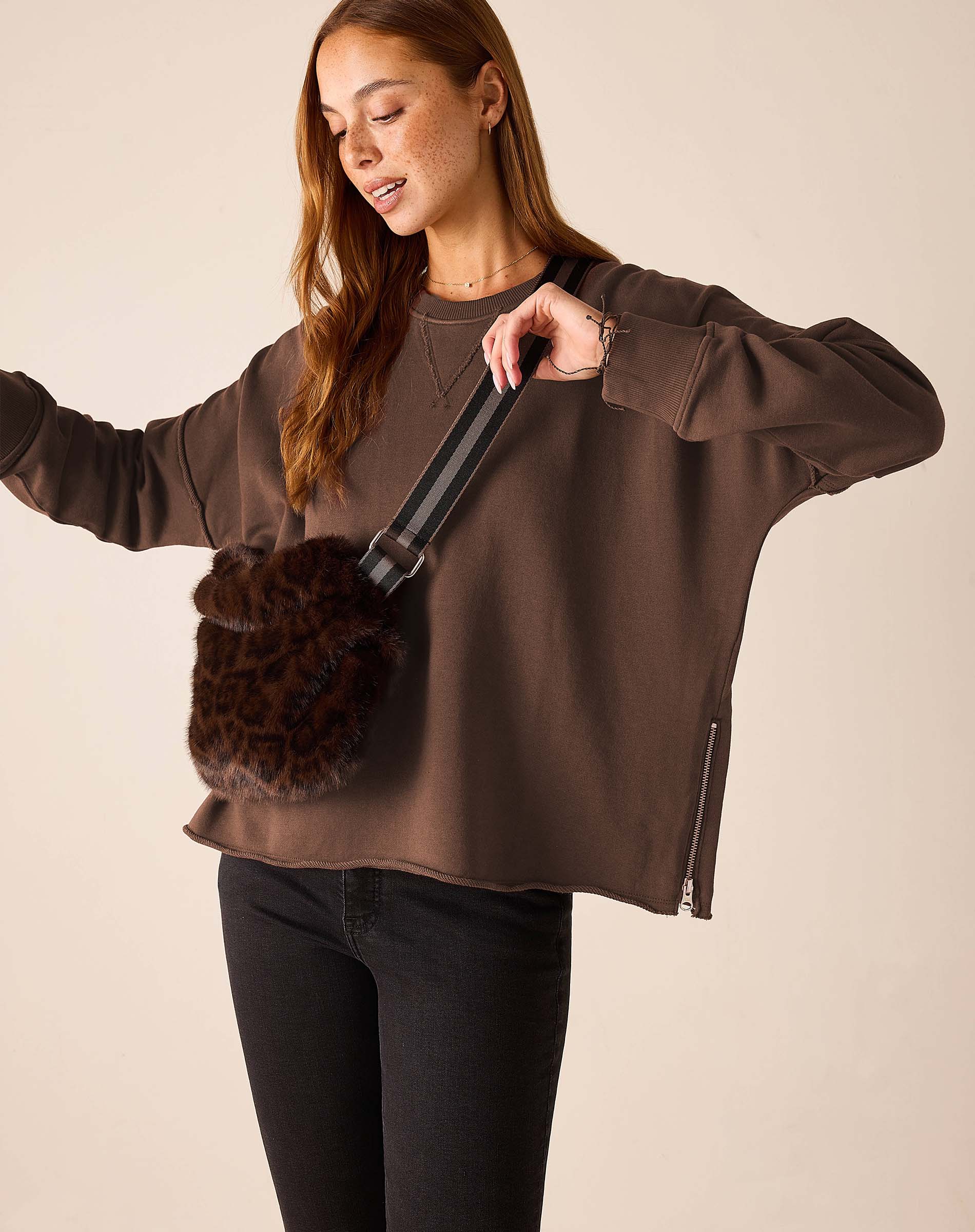 Woman wearing Mer-Sea Frenchie Zip Side Crewneck in espresso brown with faux fur crossbody bag