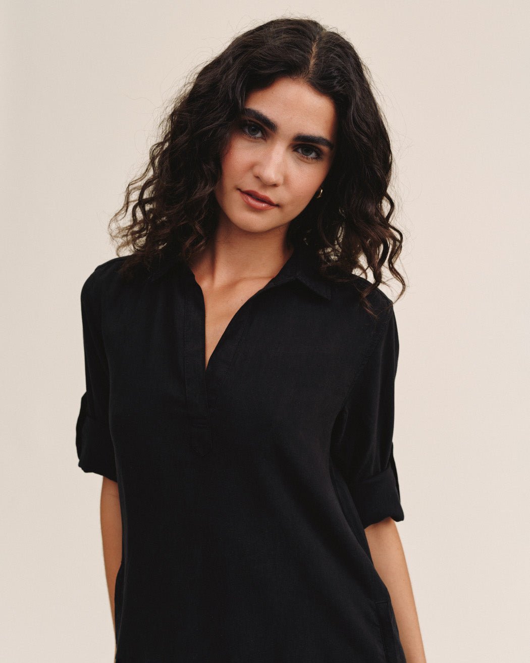 Woman wearing black long sleeve A-line dress with V-neck and rolled sleeves
