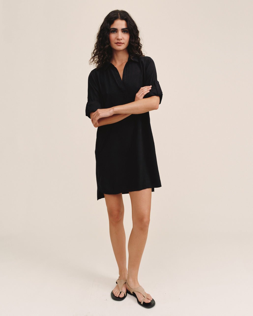 Woman wearing black long sleeve A-line shirt dress with v-neck and rolled sleeves