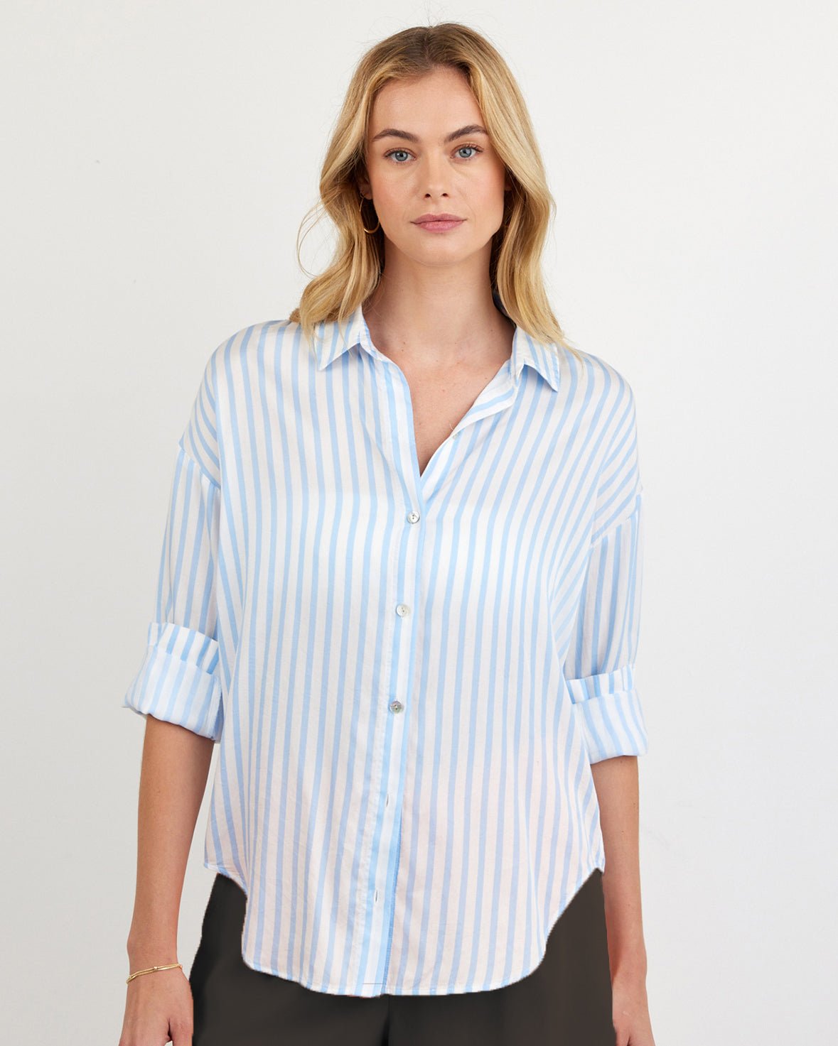 Woman wearing oversized blue and white striped button-down shirt with rolled sleeves