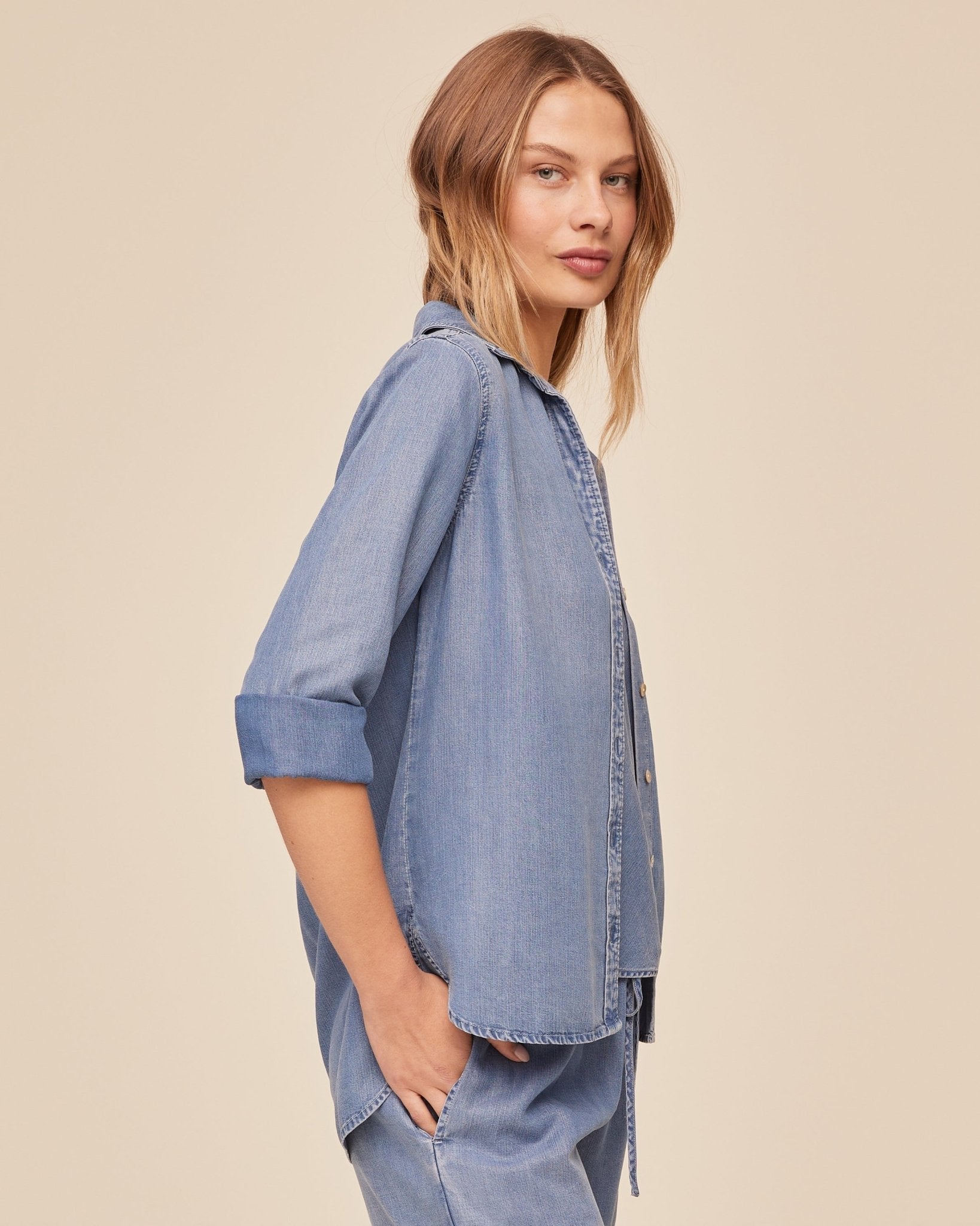 Woman wearing BELLA DAHL indigo denim button-down shirt with rolled sleeves and relaxed fit