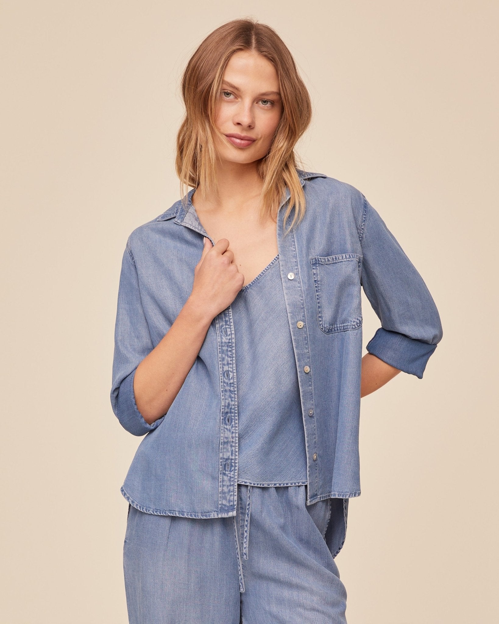 Woman wearing BELLA DAHL indigo blue denim button-down shirt with rolled sleeves
