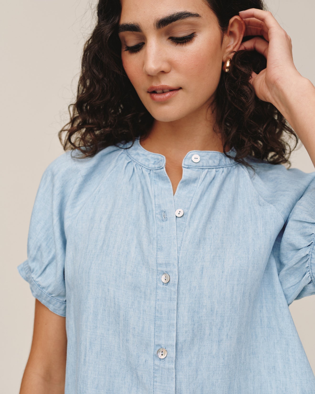 Woman wearing light blue chambray short sleeve button-up shirt with rolled sleeves