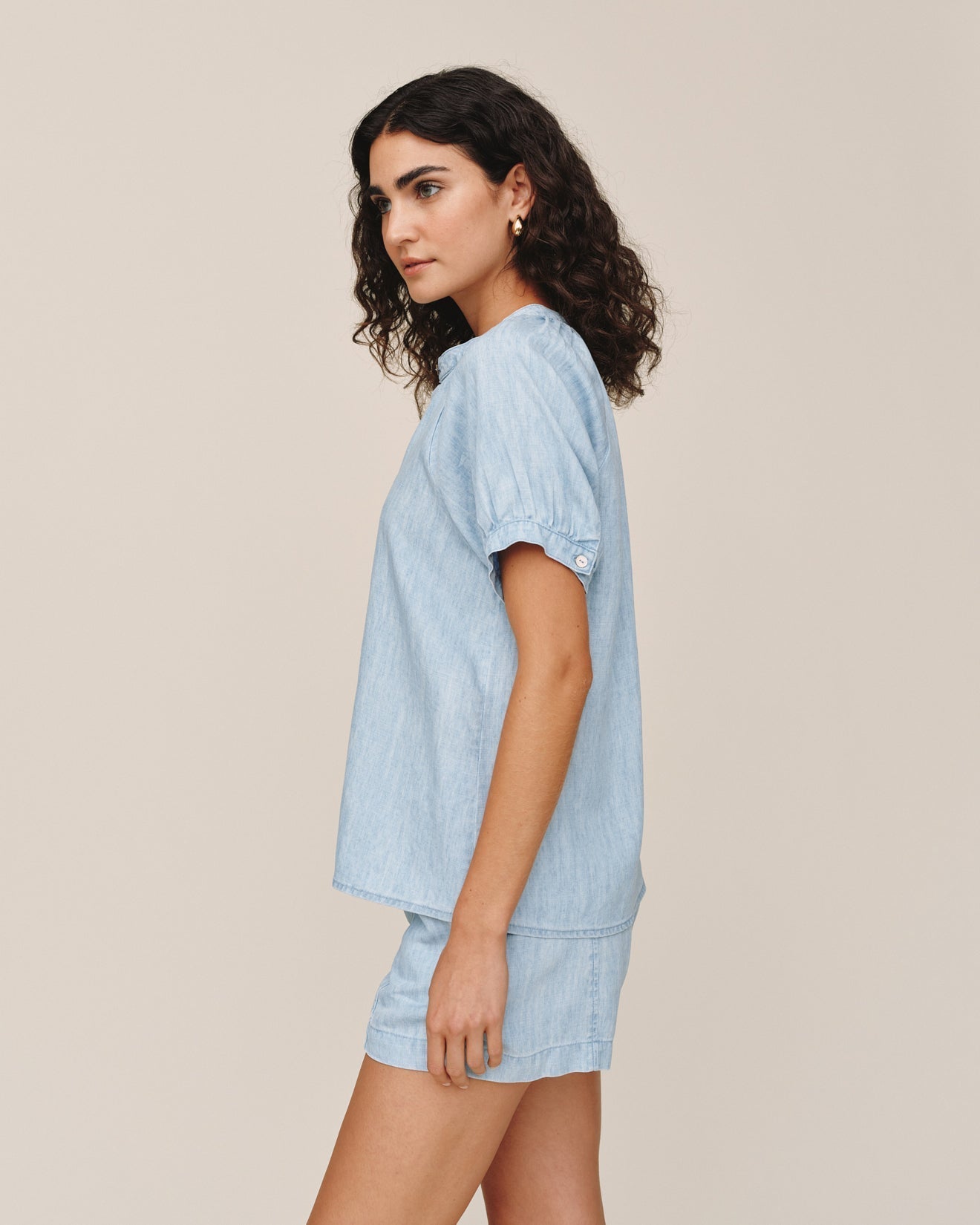 Woman wearing light blue denim short sleeve raglan shirt and matching shorts set