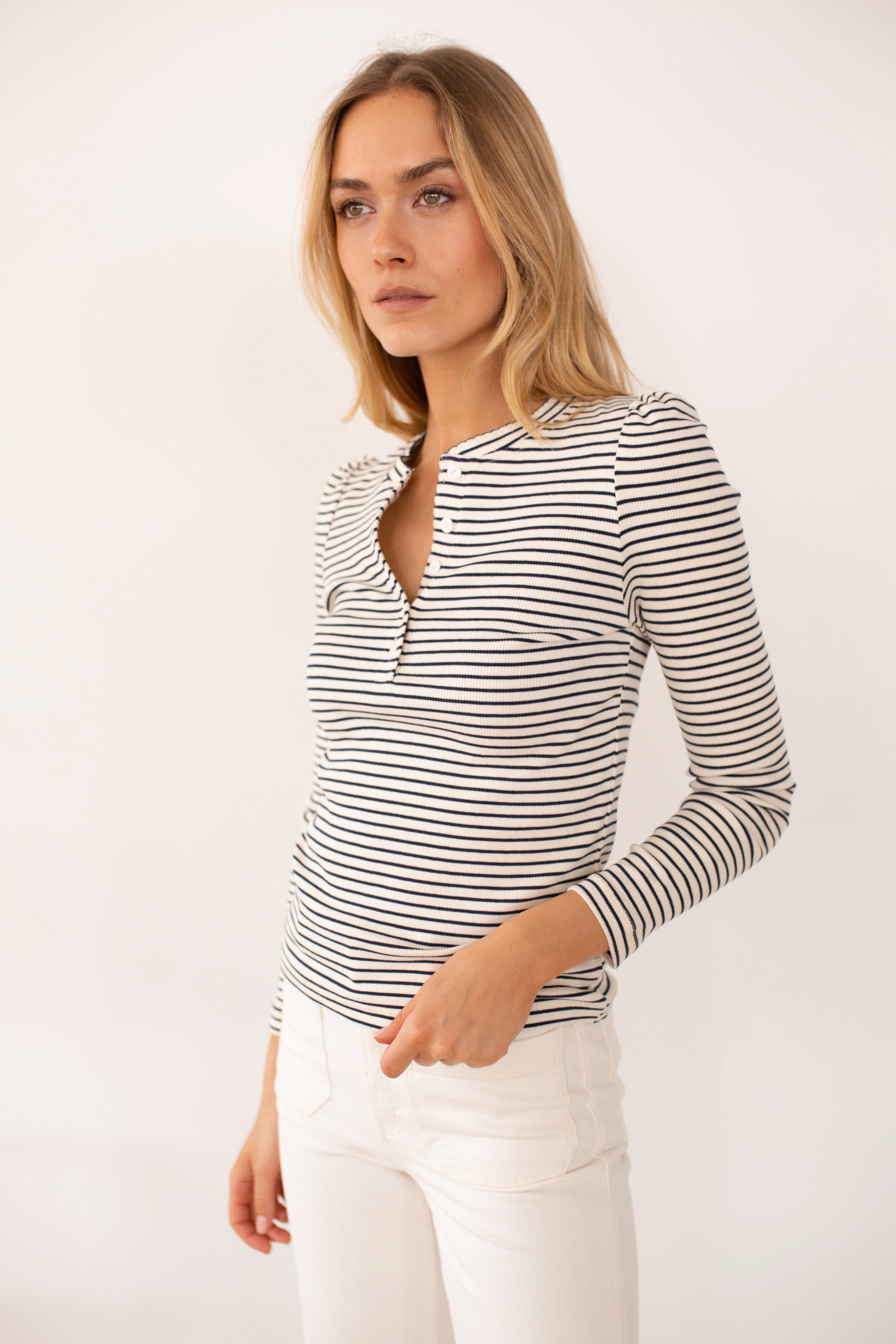 Woman wearing navy and ivory striped puff sleeve henley top with white pants